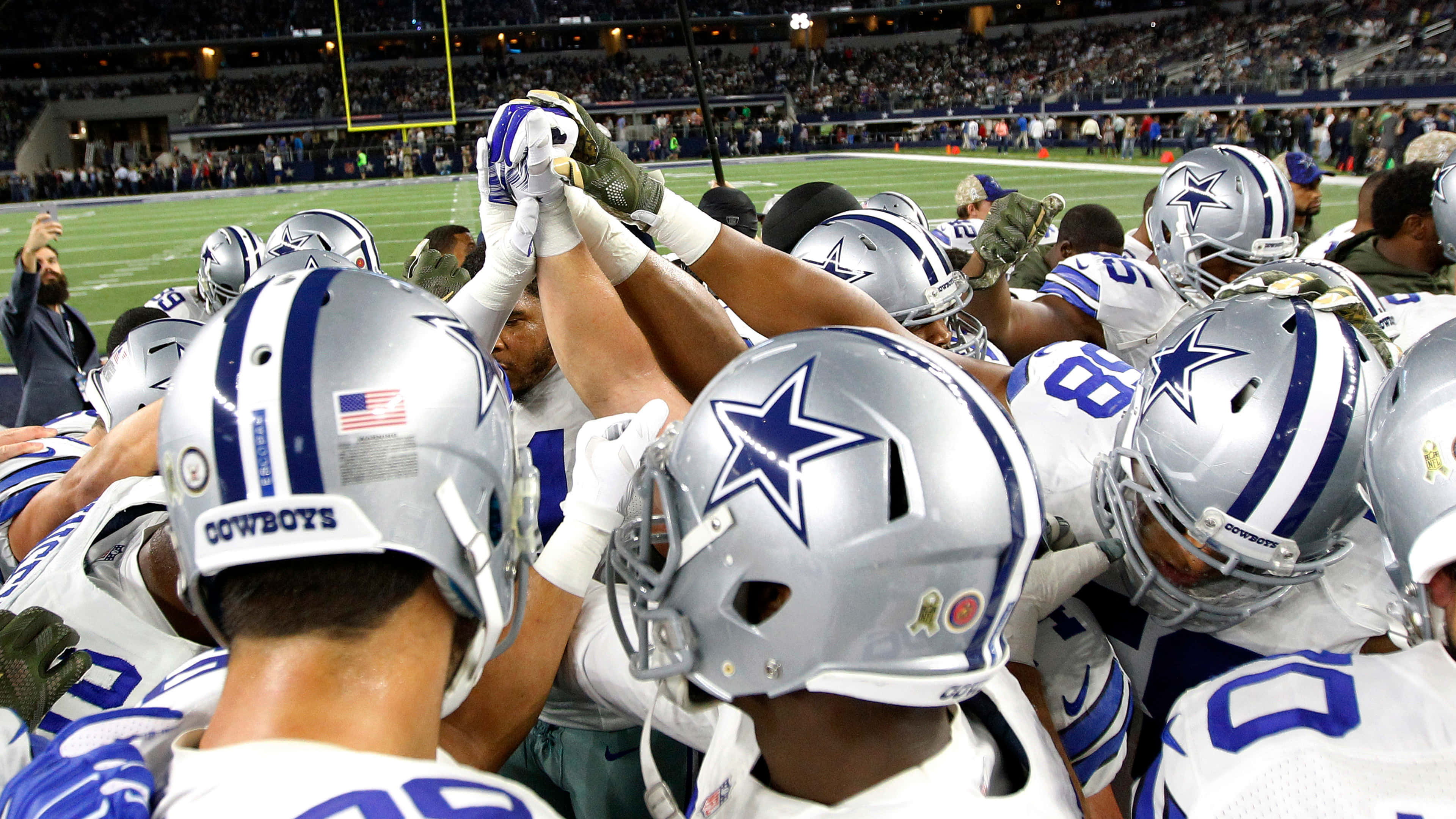 Dallas Cowboys Players 桌布 壁紙 — 達拉斯牛仔隊的足球員在比賽中緊密圍攏，舉手團結一致。