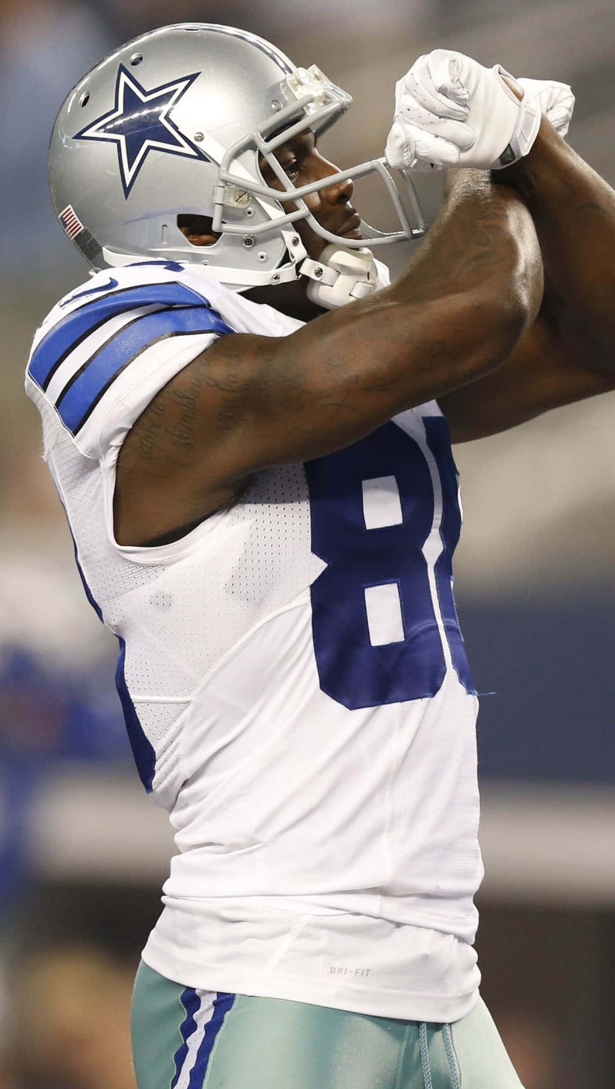 Dallas Cowboys Players 桌布 壁紙 — 達拉斯牛仔隊美式足球球員88號身穿白色和藍色球衣，在體育場燈光下比賽中高舉雙臂慶祝。