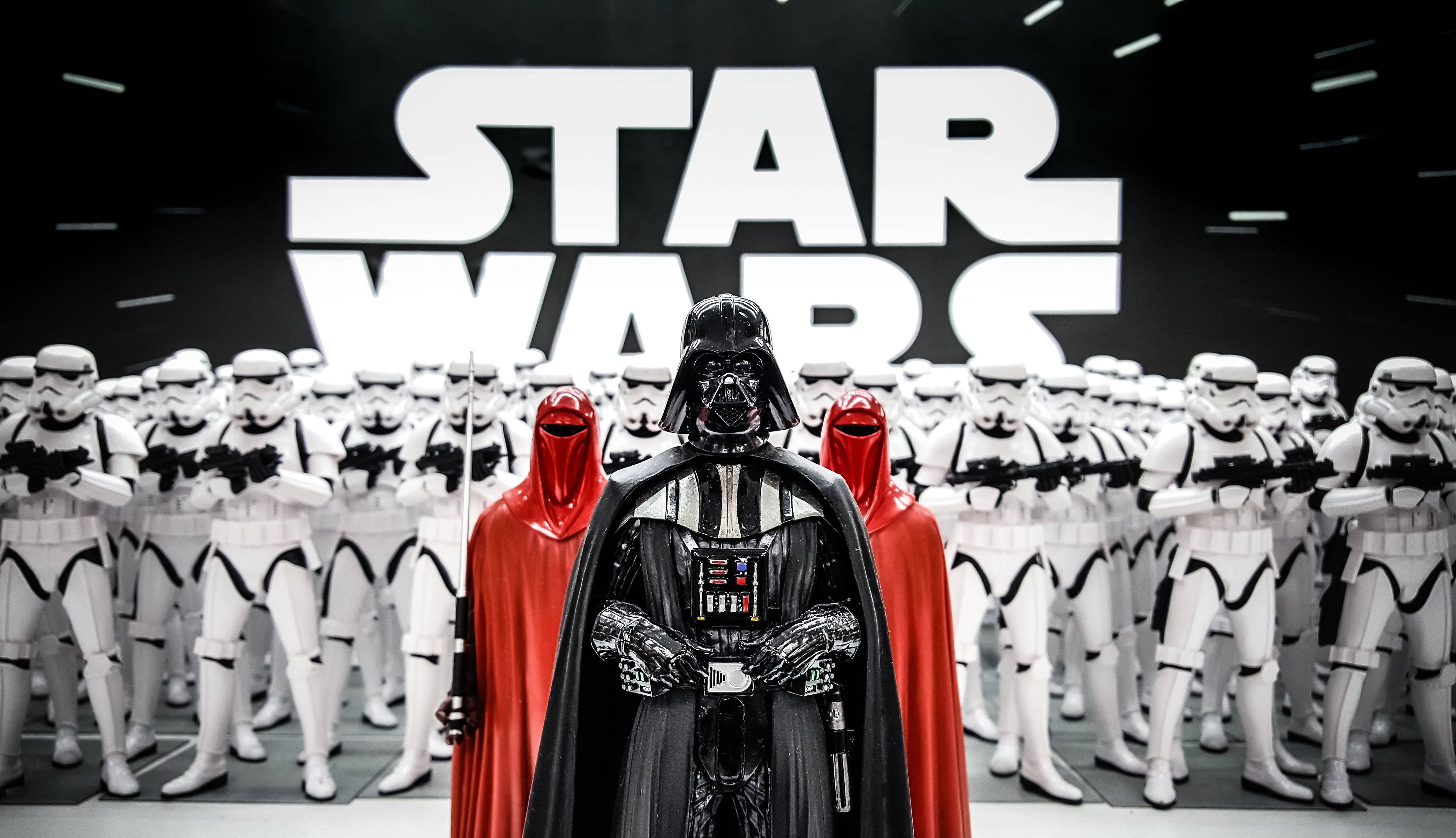 Vader 桌布 壁紙 — 達斯維達在巨大的星際大戰標誌下，威嚴地站在一群風暴兵面前，兩側有紅色斗篷人物。