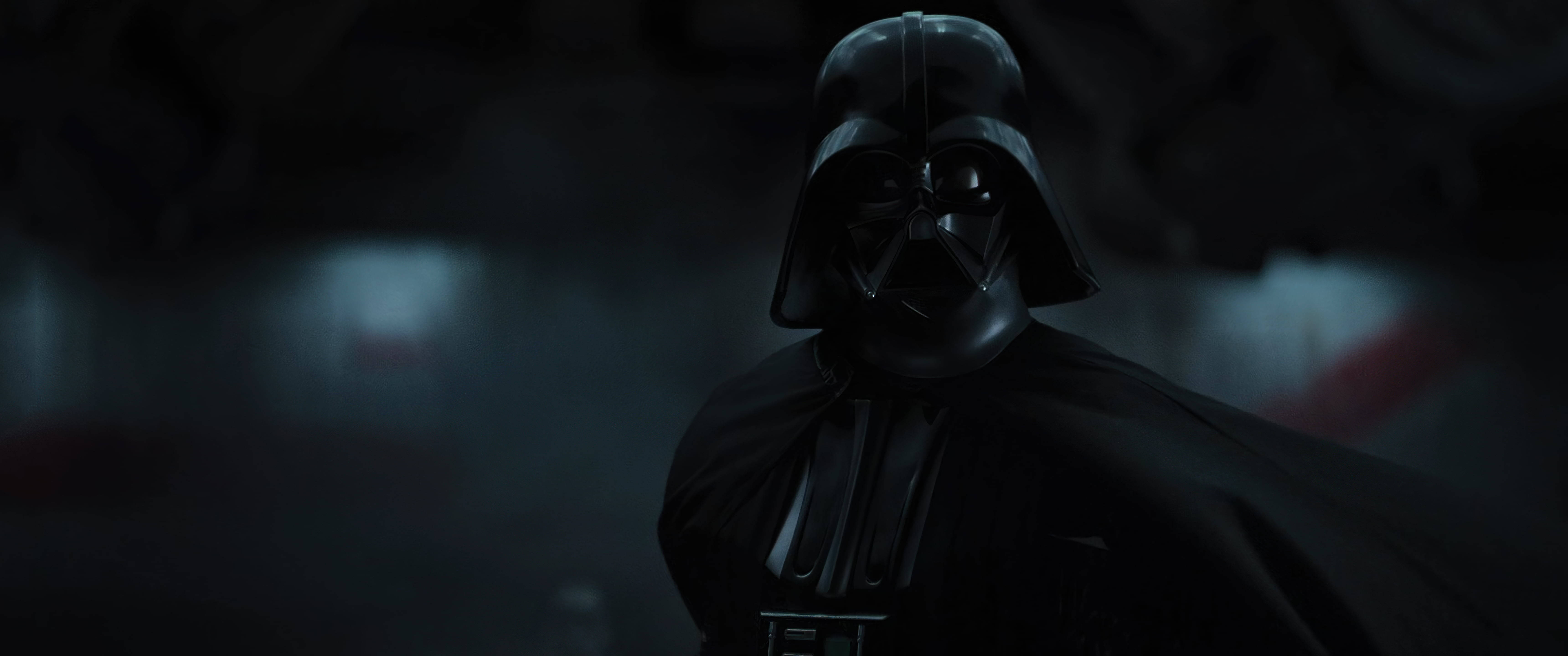 Vader 桌布 壁紙 — 達斯維達站在陰暗的陰影中，身後隱約可見發光的紅色光劍柄。