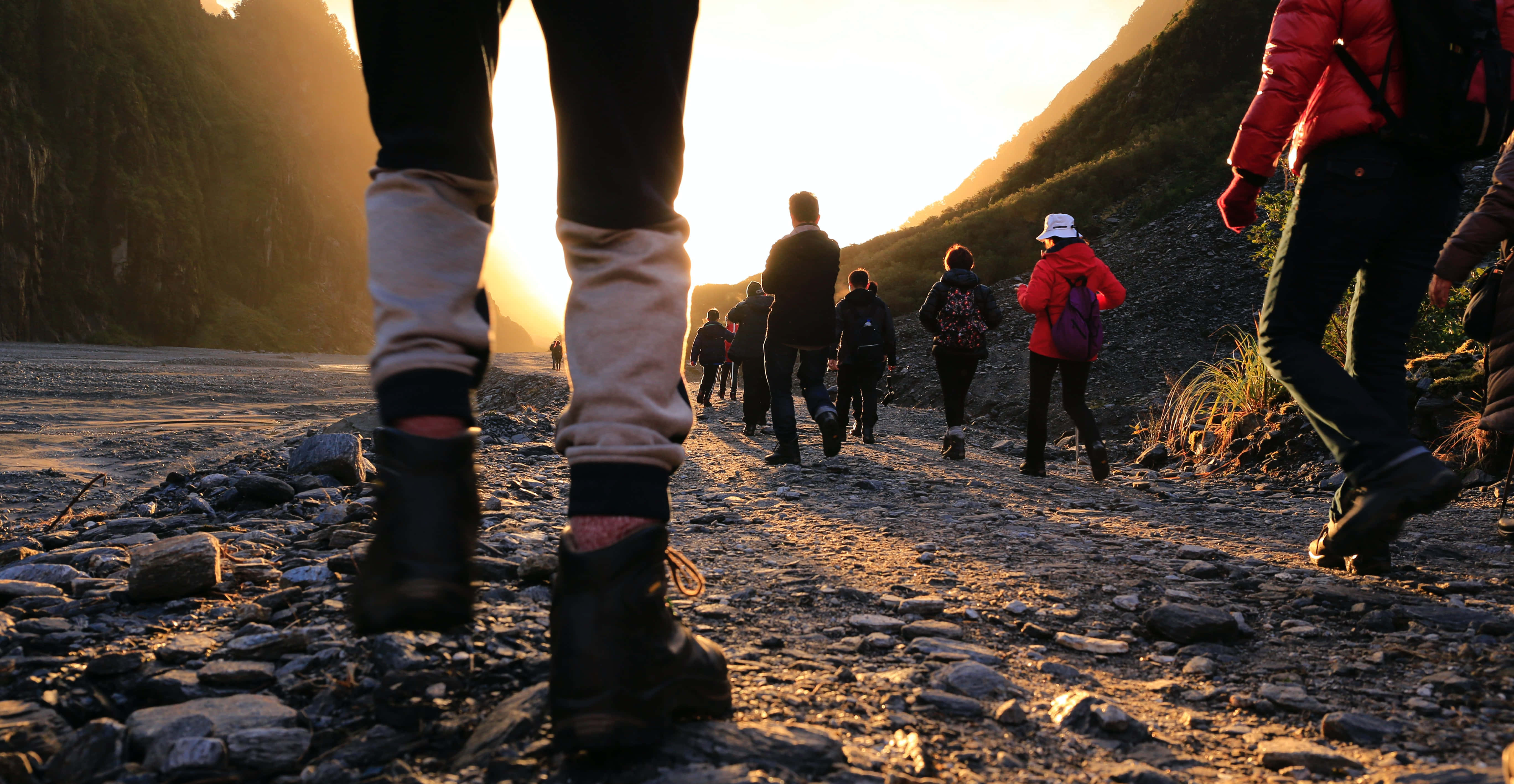 Hiking 桌布 壁紙 — 遠足者沿著岩石山徑徒步，金色夕陽灑滿崎嶇小徑和陡峭懸崖。