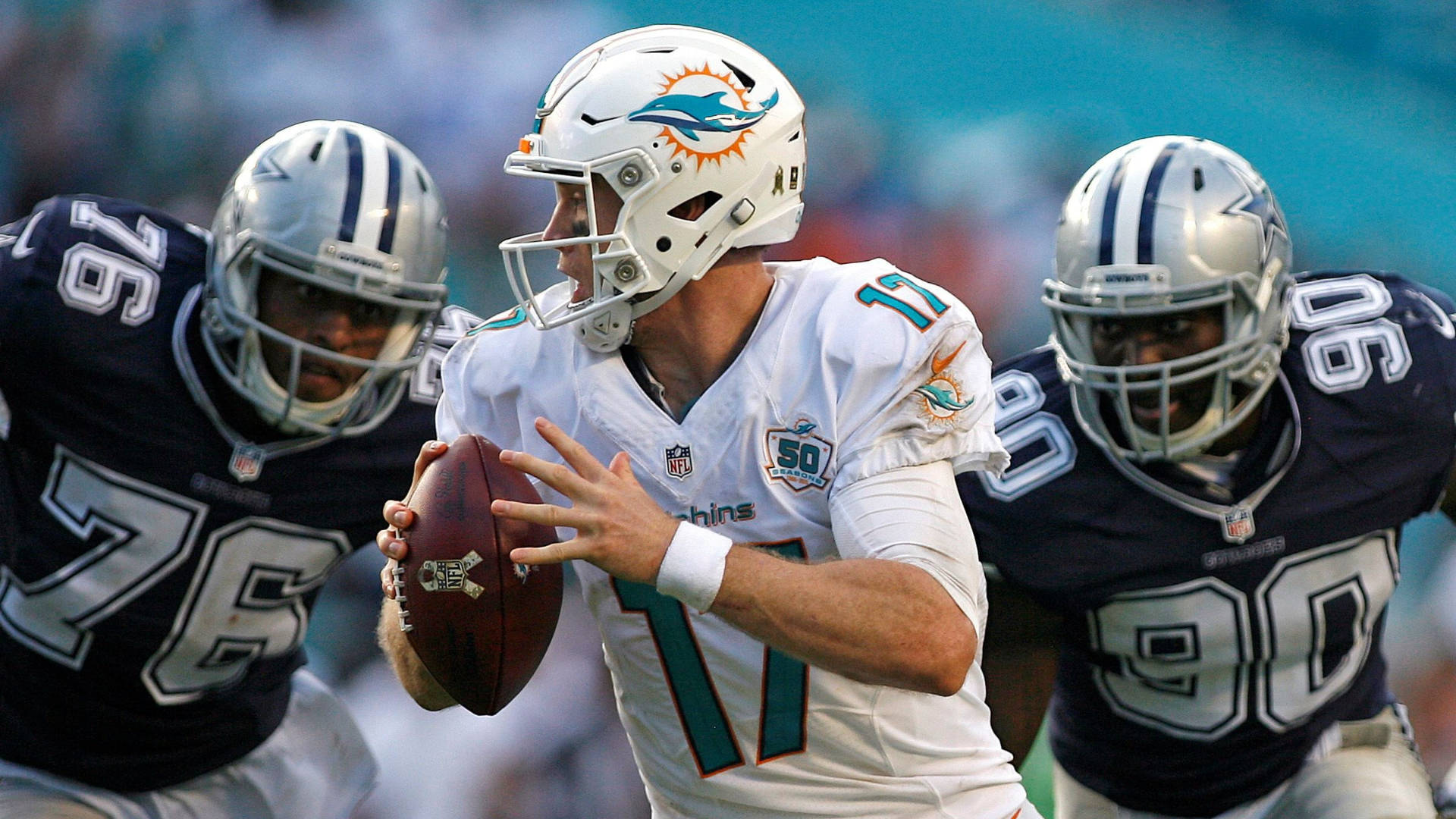 dolphins 桌布 壁紙 — 邁阿密海豚隊四分衛身穿白色球衣在球場投擲橄欖球，兩名達拉斯牛仔隊防守球員向他施壓。