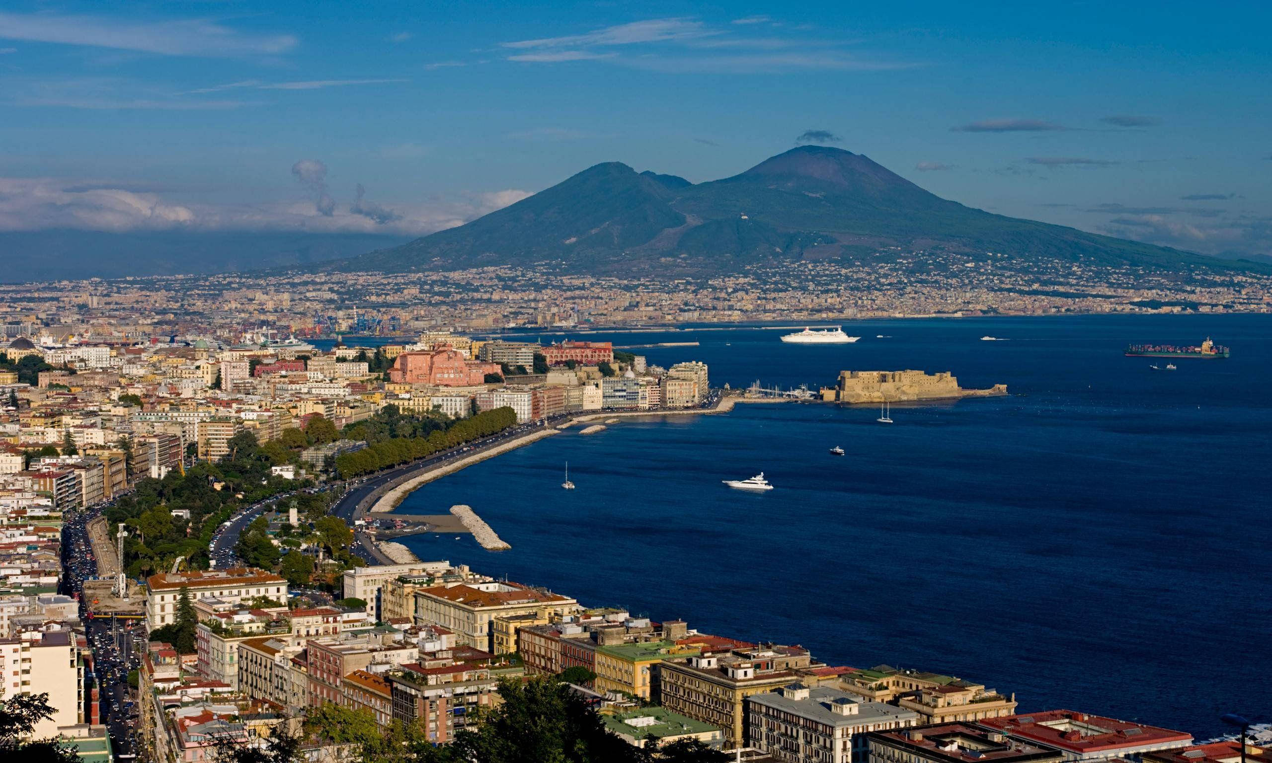 Naples 桌布 壁紙 — 那不勒斯的全景視圖，維蘇威火山聳立於城市和停滿船隻的港口之上，天空清澈湛藍。