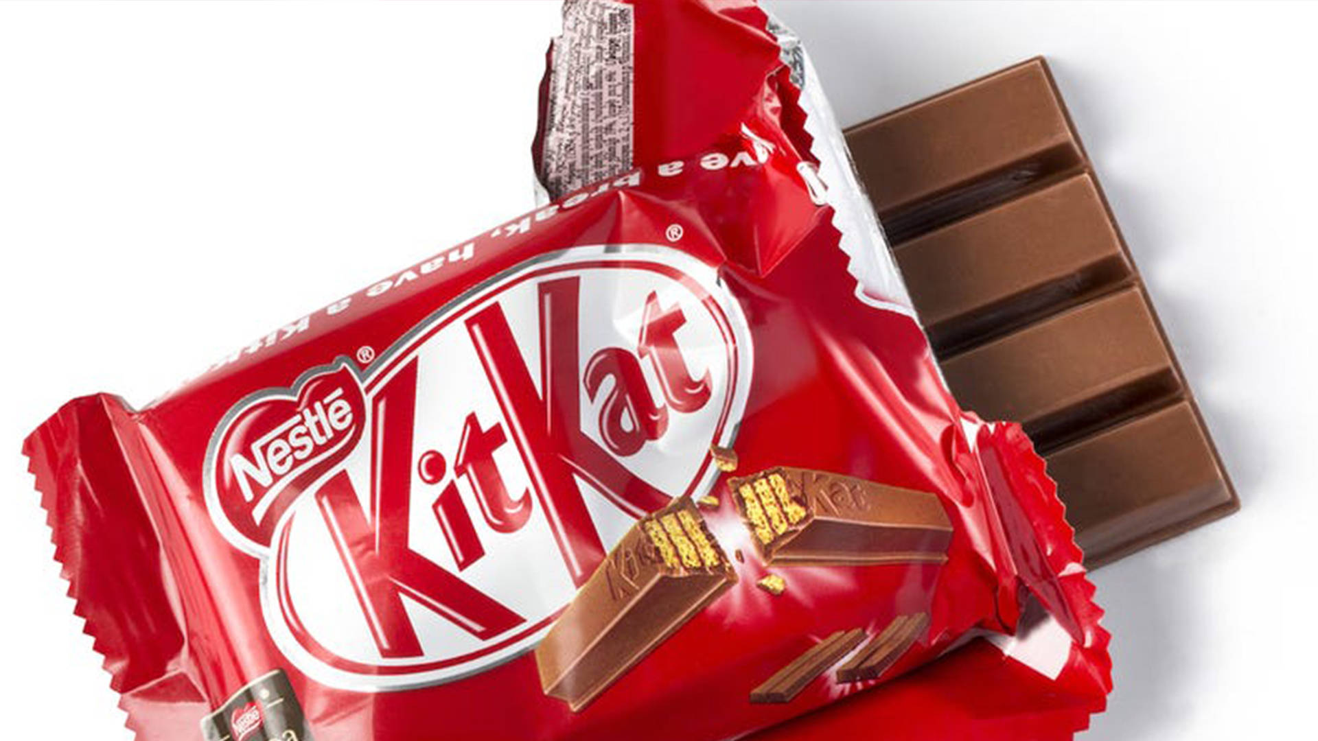 Chocolate 桌布 壁紙 — 部分拆開的 KitKat 巧克力棒，紅色錫箔包裝，破開的部份露出牛奶巧克力和威化。
