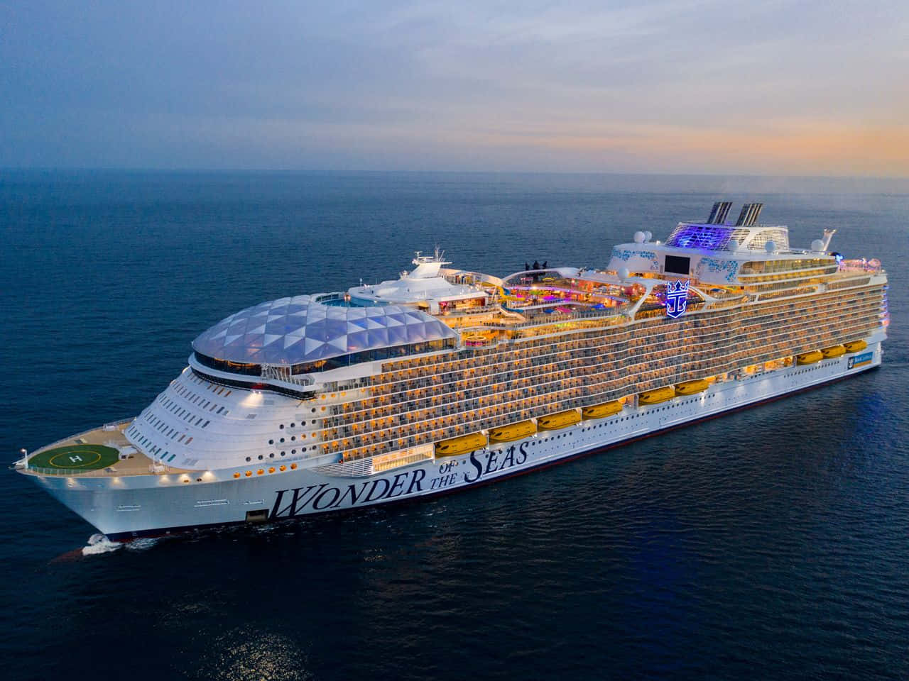Cruise 桌布 壁紙 — 郵輪Wonder of the Seas在日落時分航行，甲板閃爍，海面平靜的鳥瞰圖。