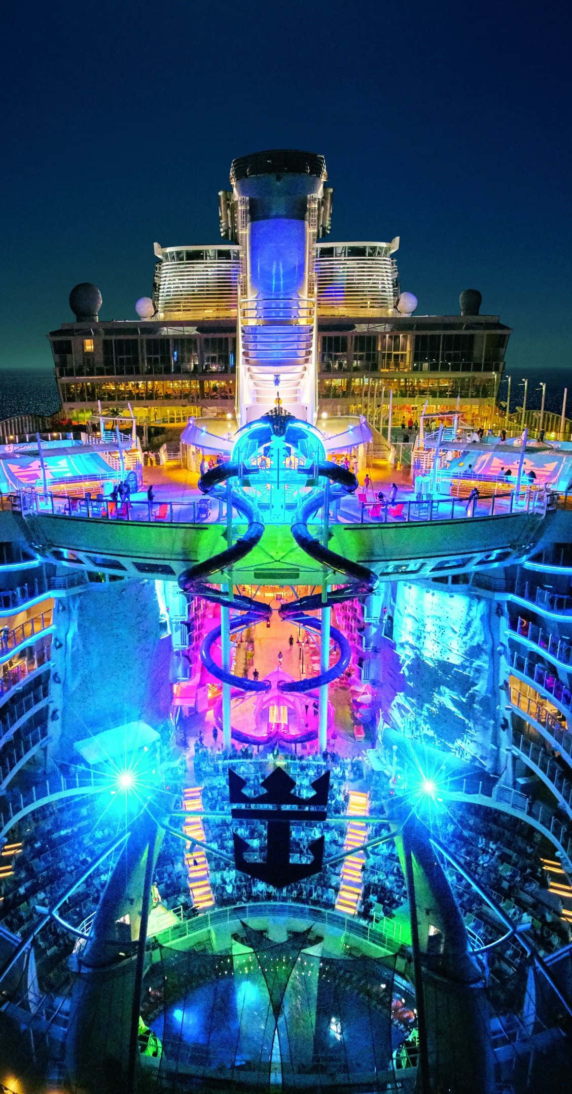 Cruise 桌布 壁紙 — 郵輪上層甲板和泳池在黑暗海洋中反射出鮮豔霓虹燈光的耀眼夜景。