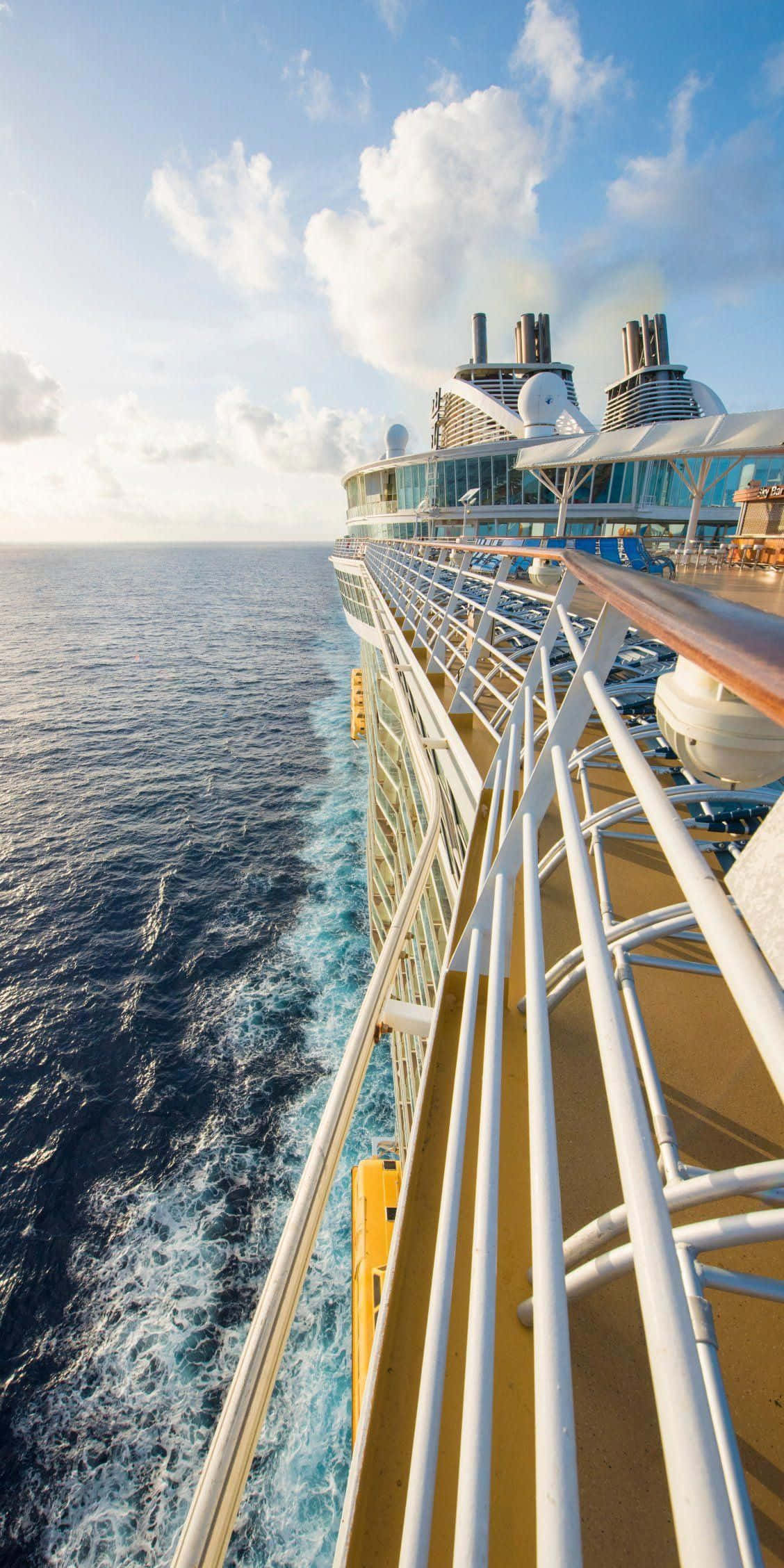 Cruise 桌布 壁紙 — 郵輪甲板俯瞰深藍色海浪，天空明亮，雲朵蓬鬆。