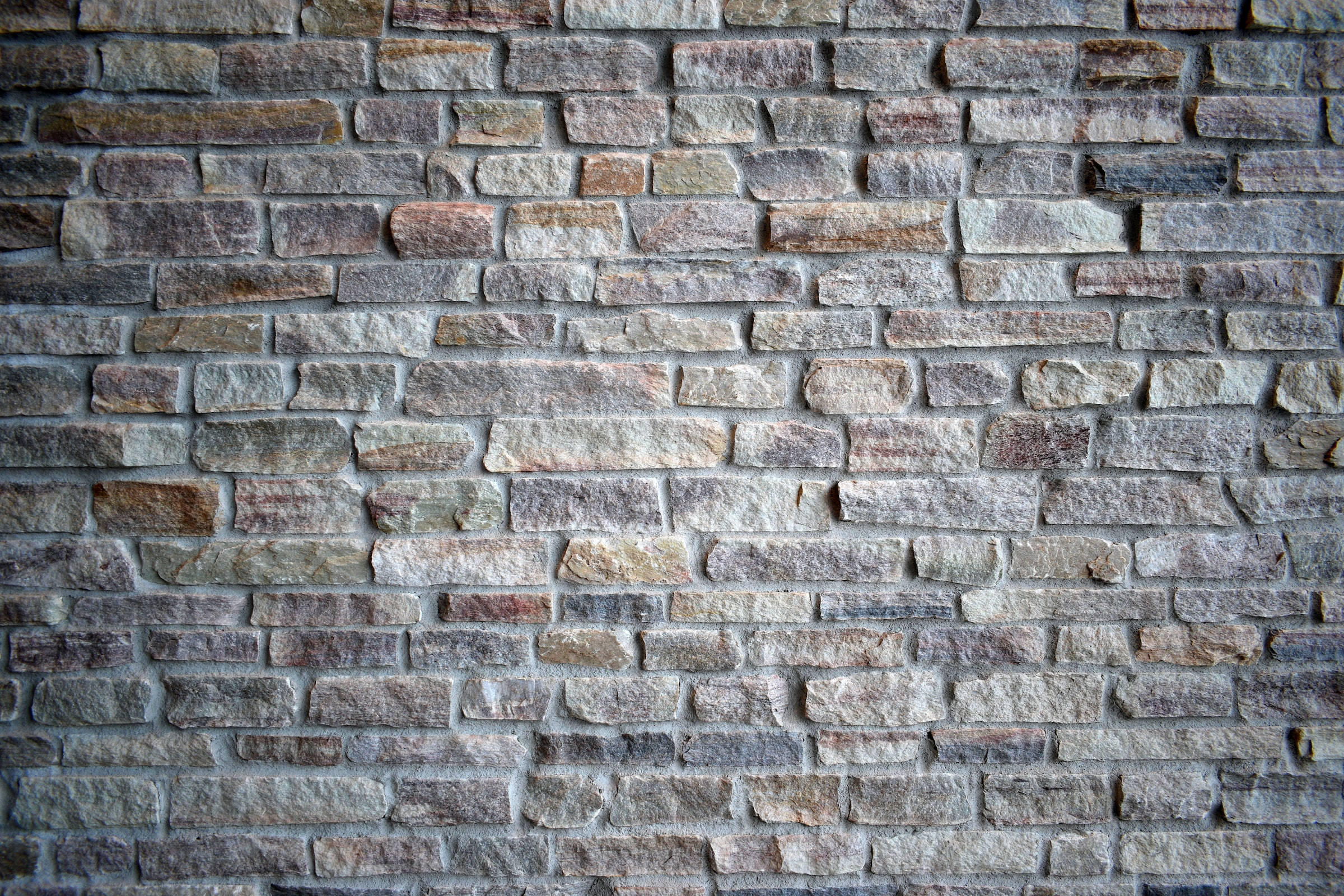 Brick 桌布 壁紙 — 鄉村風格石牆的特寫，呈現多種大地色調和紋理灰泥線條。