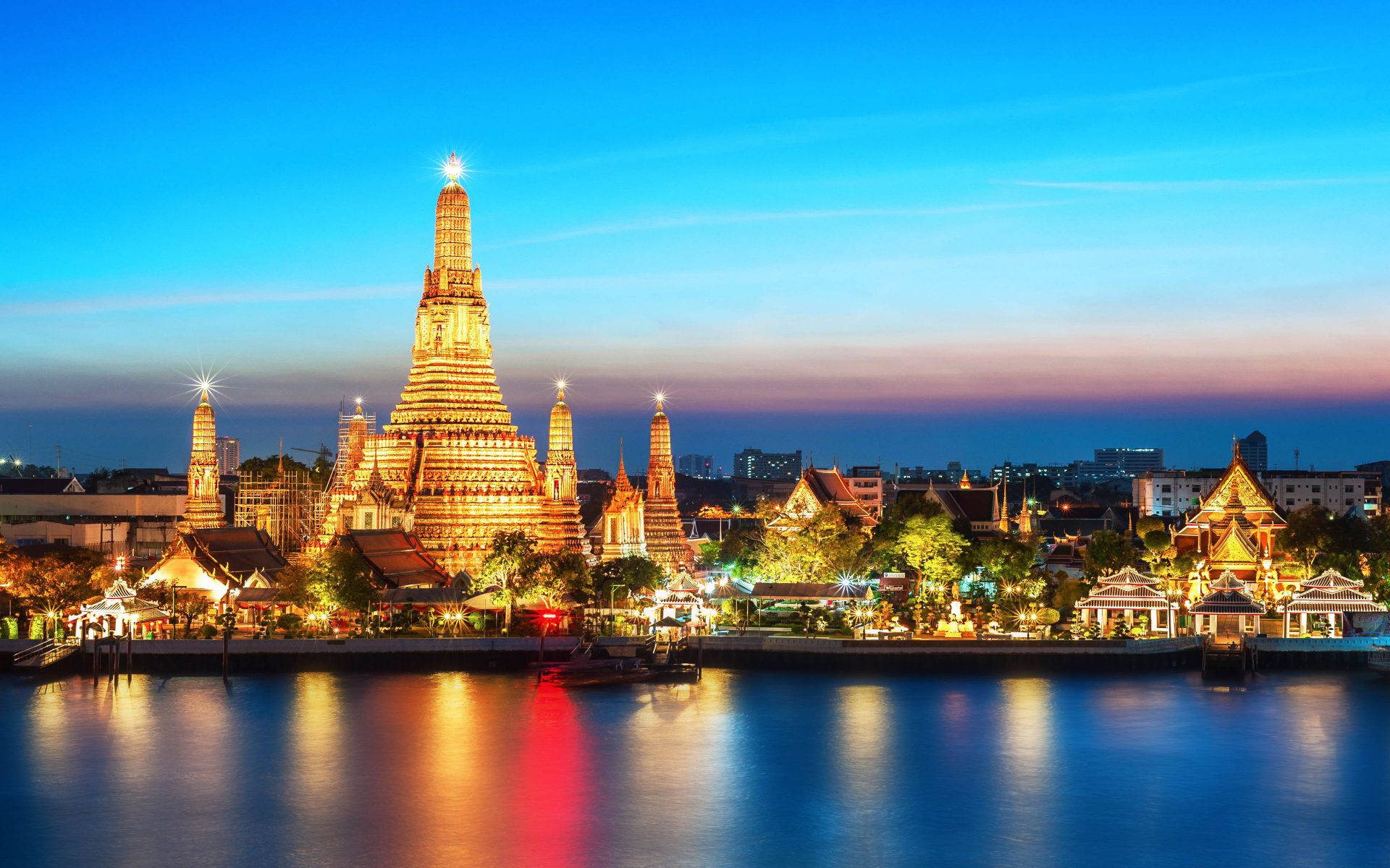 Bangkok 桌布 壁紙 — 鄭王廟的金色佛塔尖頂在暮色天空下閃耀，倒映在平靜的河水之中。