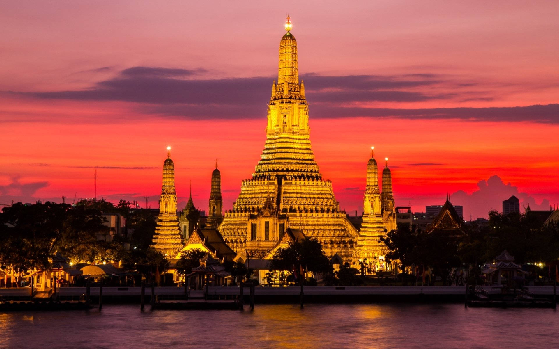 Bangkok 桌布 壁紙 — 鄭王廟的金色佛塔尖頂在火紅的日落天空映襯下閃耀，倒映在平靜的河水之中。