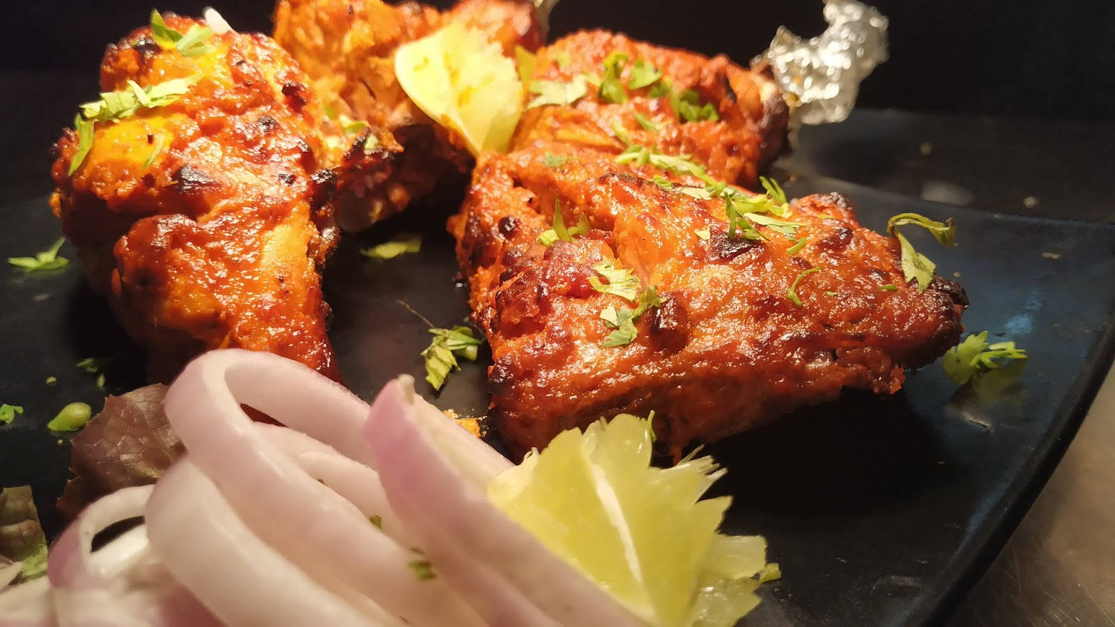 fried chicken 桌布 壁紙 — 酥脆的坦都里雞塊閃耀著香料光澤，在深色盤子上以新鮮香菜和檸檬角裝飾。
