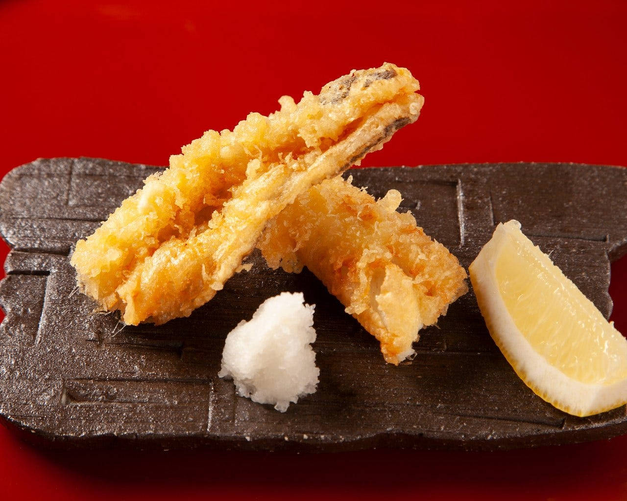 shrimp 桌布 壁紙 — 酥脆金黃天婦羅塊搭配檸檬角及白醬，置於深色石盤上，襯以鮮紅背景。