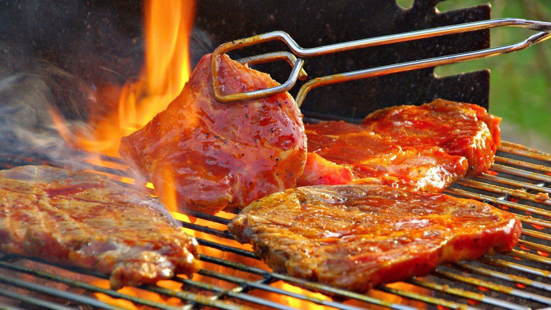 meat 桌布 壁紙 — 醃製的牛排在熾熱的橙色火焰上燒烤，煙霧從熱金屬烤架上升起。
