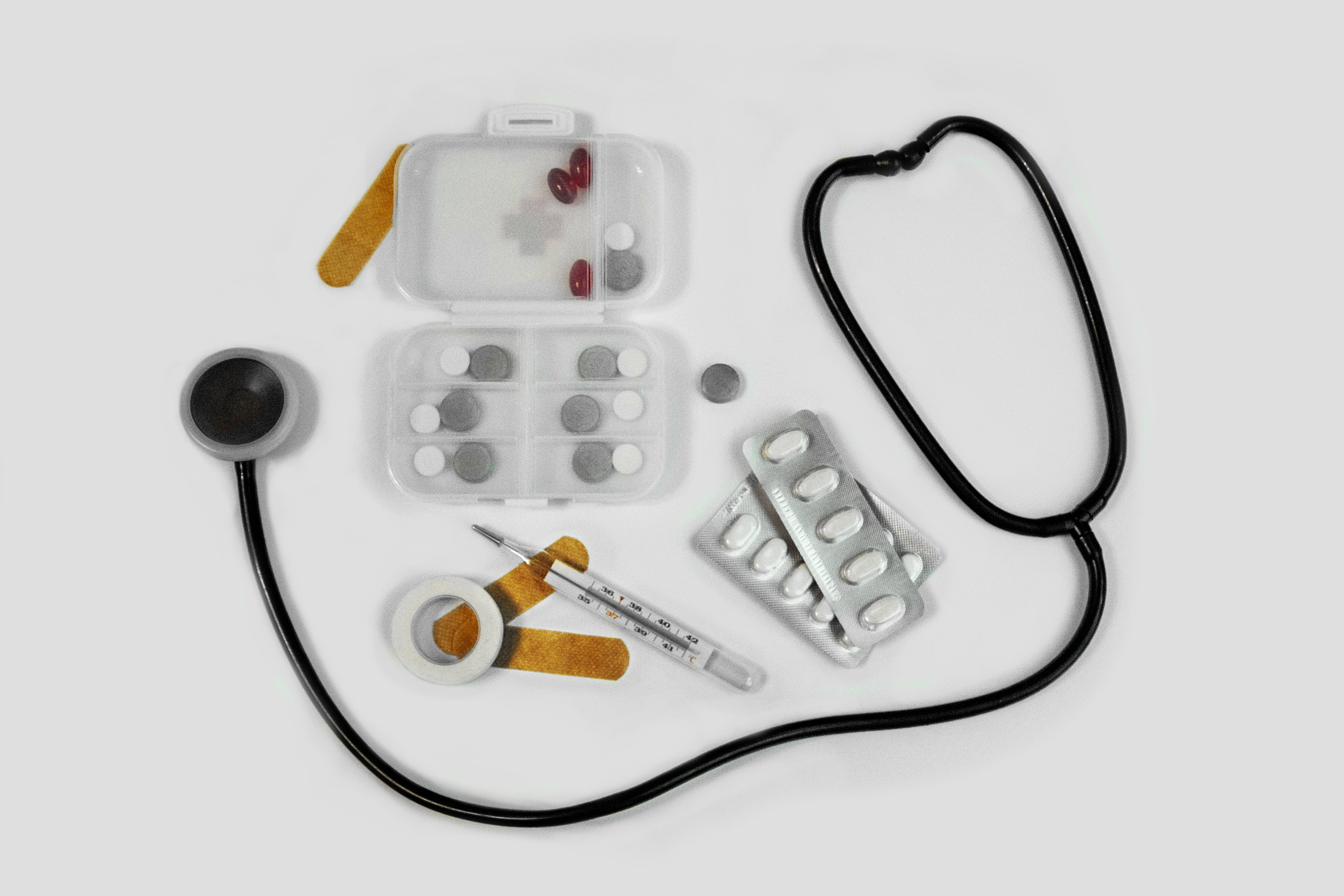 Stethoscope 桌布 壁紙 — 醫療用品平鋪擺放，包括聽診器、藥丸、繃帶和溫度計，整齊排列在乾淨的白色表面上。