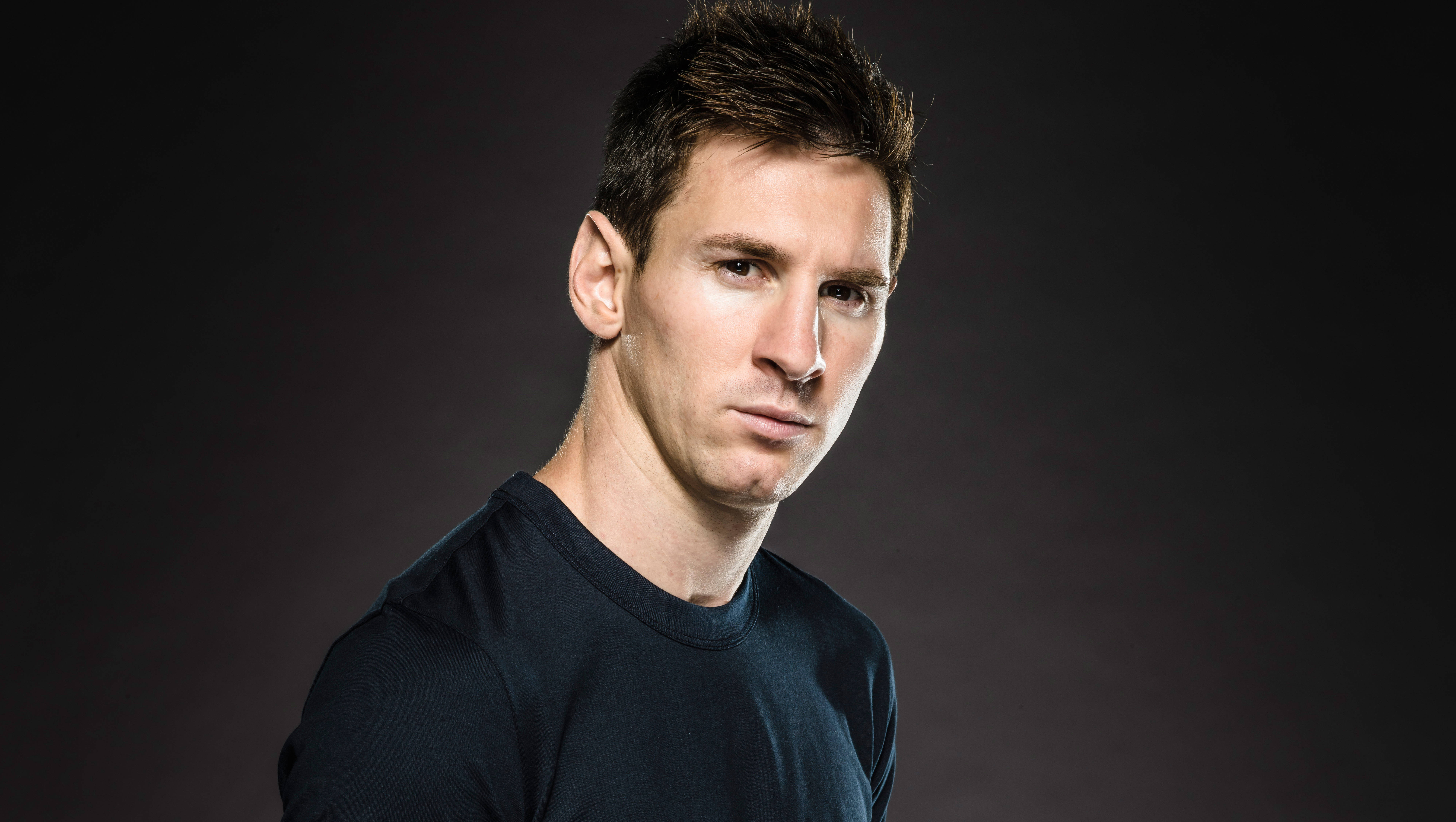 Messi 4K Ultra HD 桌布 壁紙 — 里奧內爾·梅西身穿深色T恤的頭像特寫，背景為漸變黑色，配以柔和的工作室燈光。