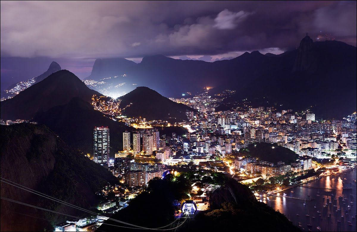 South America 桌布 壁紙 — 里約熱內盧令人驚嘆的夜景，燈火輝煌的城市景觀坐落在黑暗的山脈和閃閃發光的水濱之間。