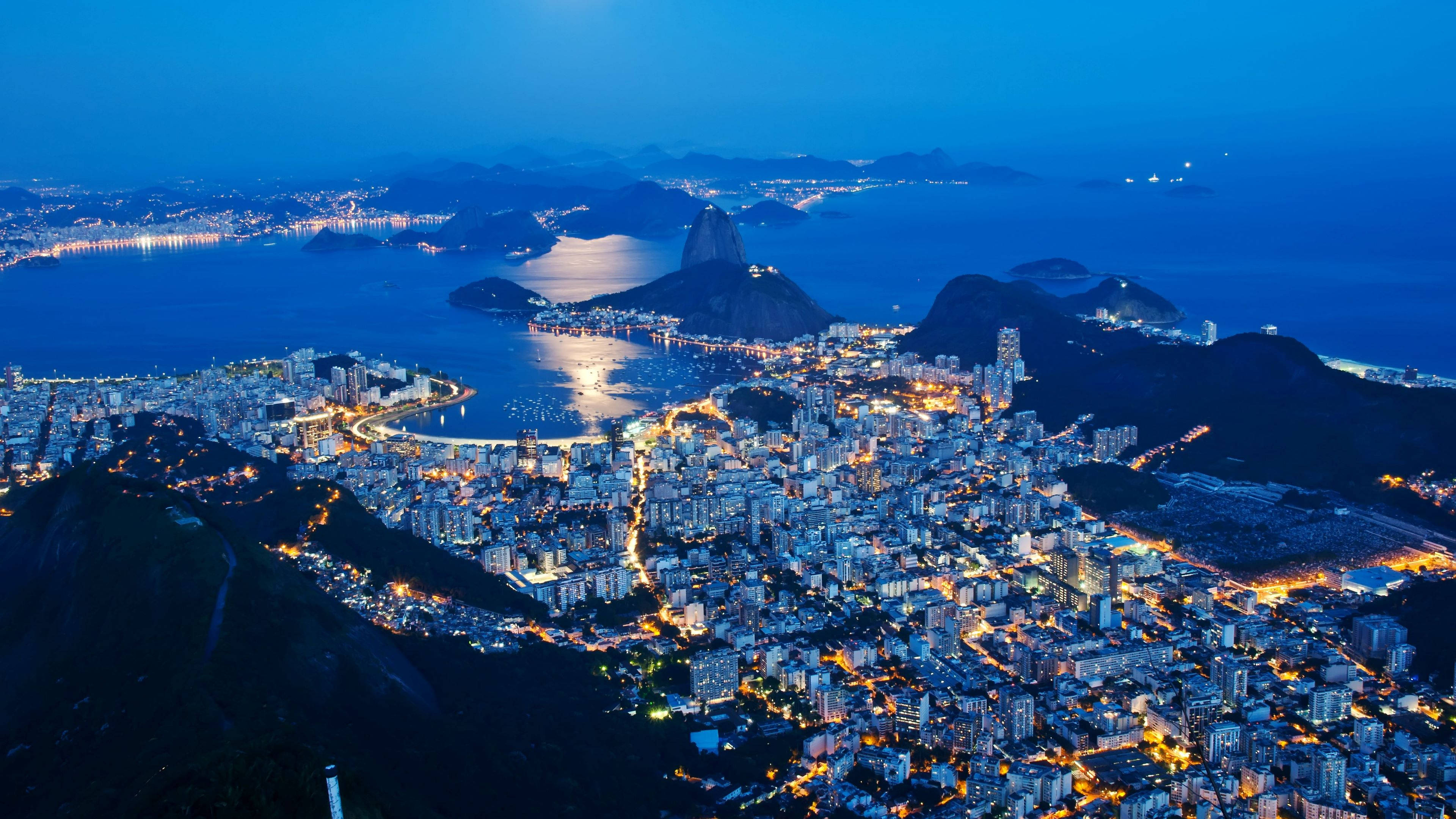 rio 桌布 壁紙 — 里約熱內盧黃昏時的鳥瞰圖，糖麵包山和城市燈光在深藍色天空中閃耀。