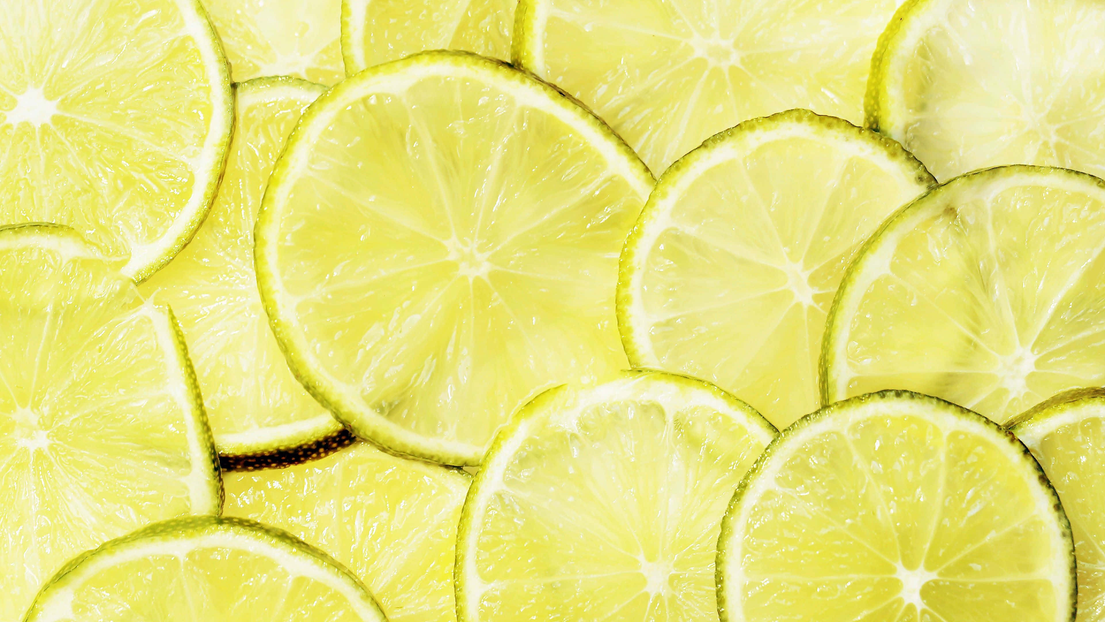 Lime 桌布 壁紙 — 重疊檸檬片的鮮明特寫，展現多汁果肉和亮黃色果皮。
