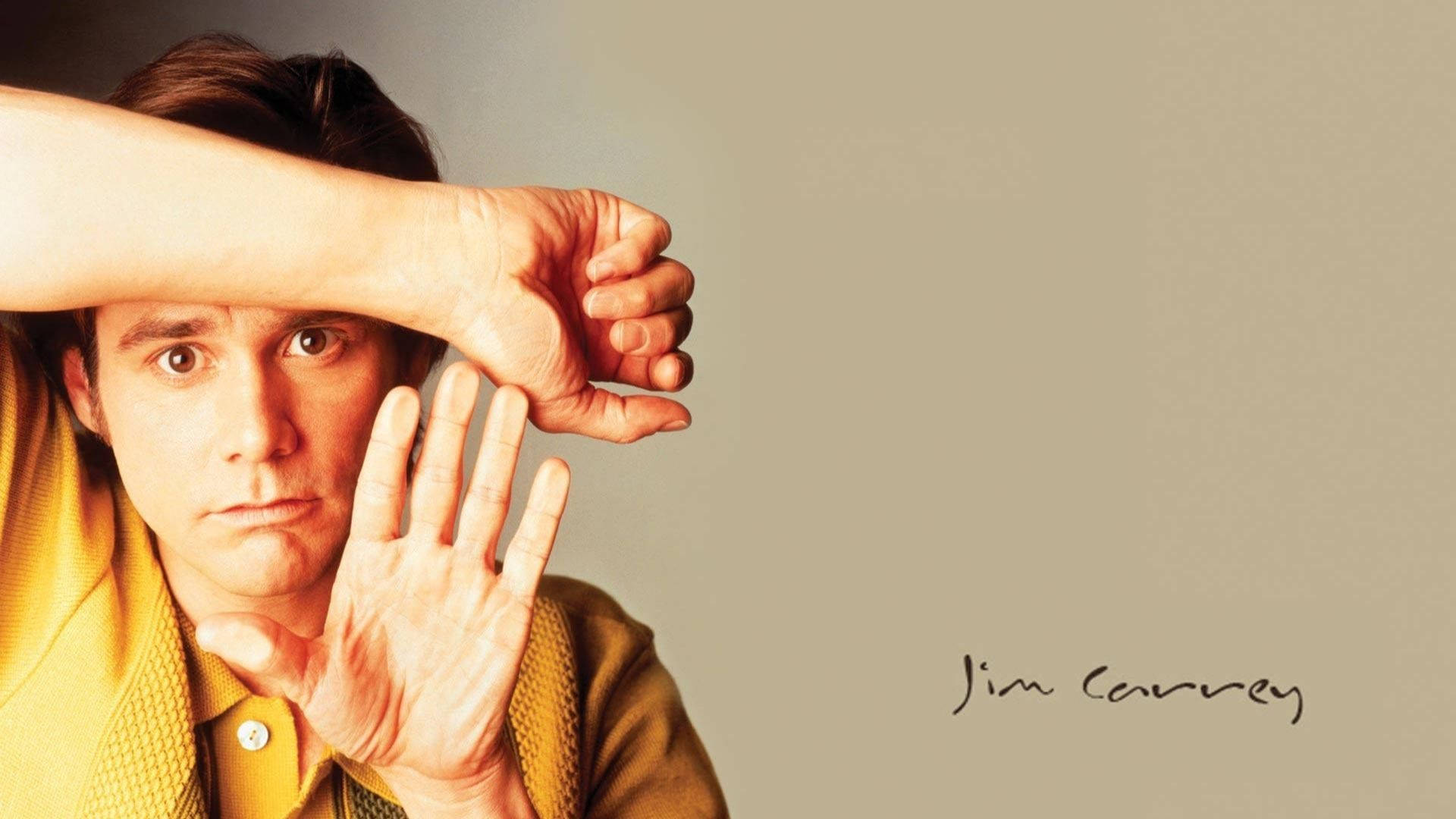 Jim Carrey 桌布 壁紙 — 金凱瑞透過手指窺視，表情既俏皮又強烈，背景為純米色。