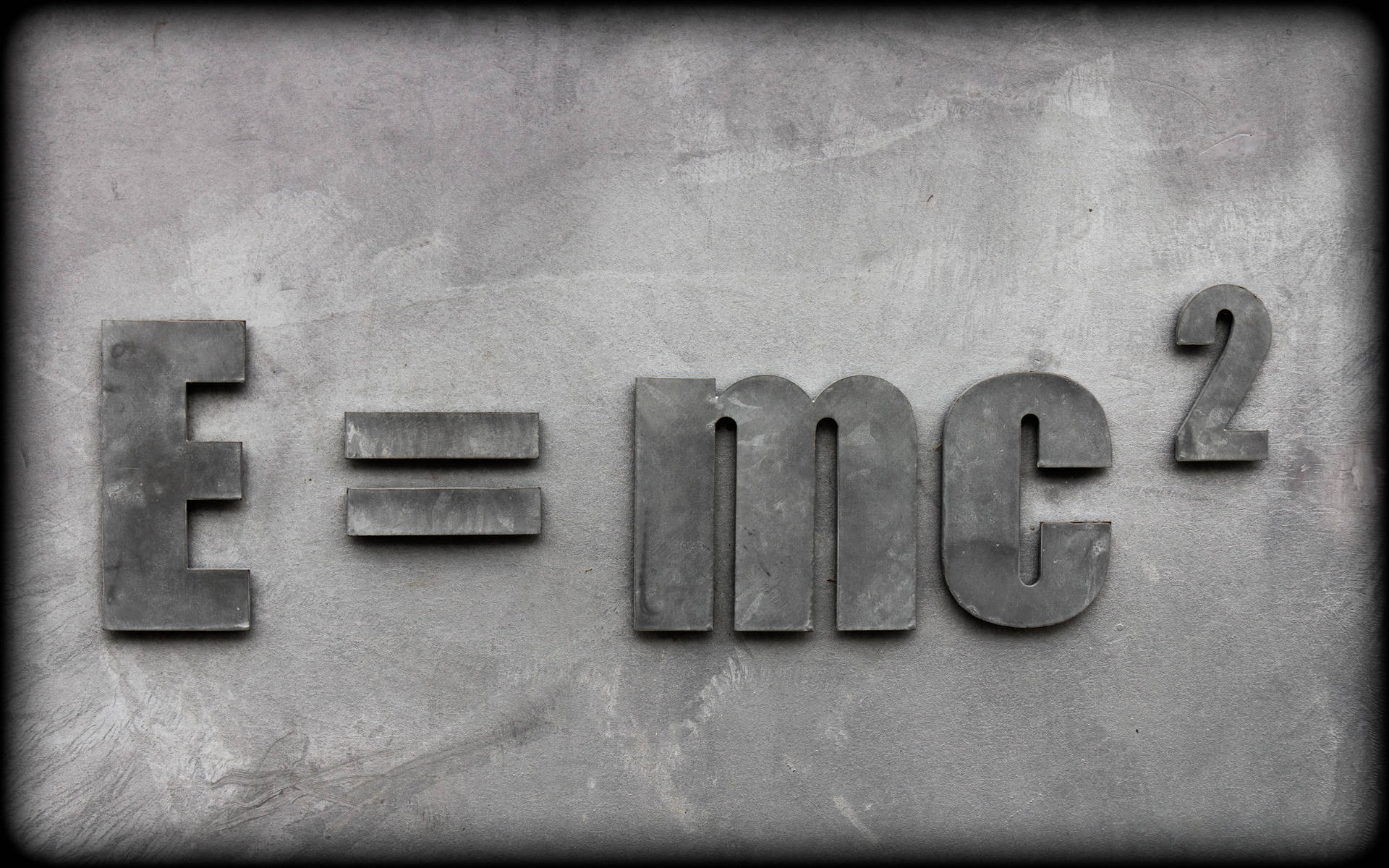 混凝土牆上凸起的金屬字母顯示E=mc²方程式。 — 科學 GIF 壁紙