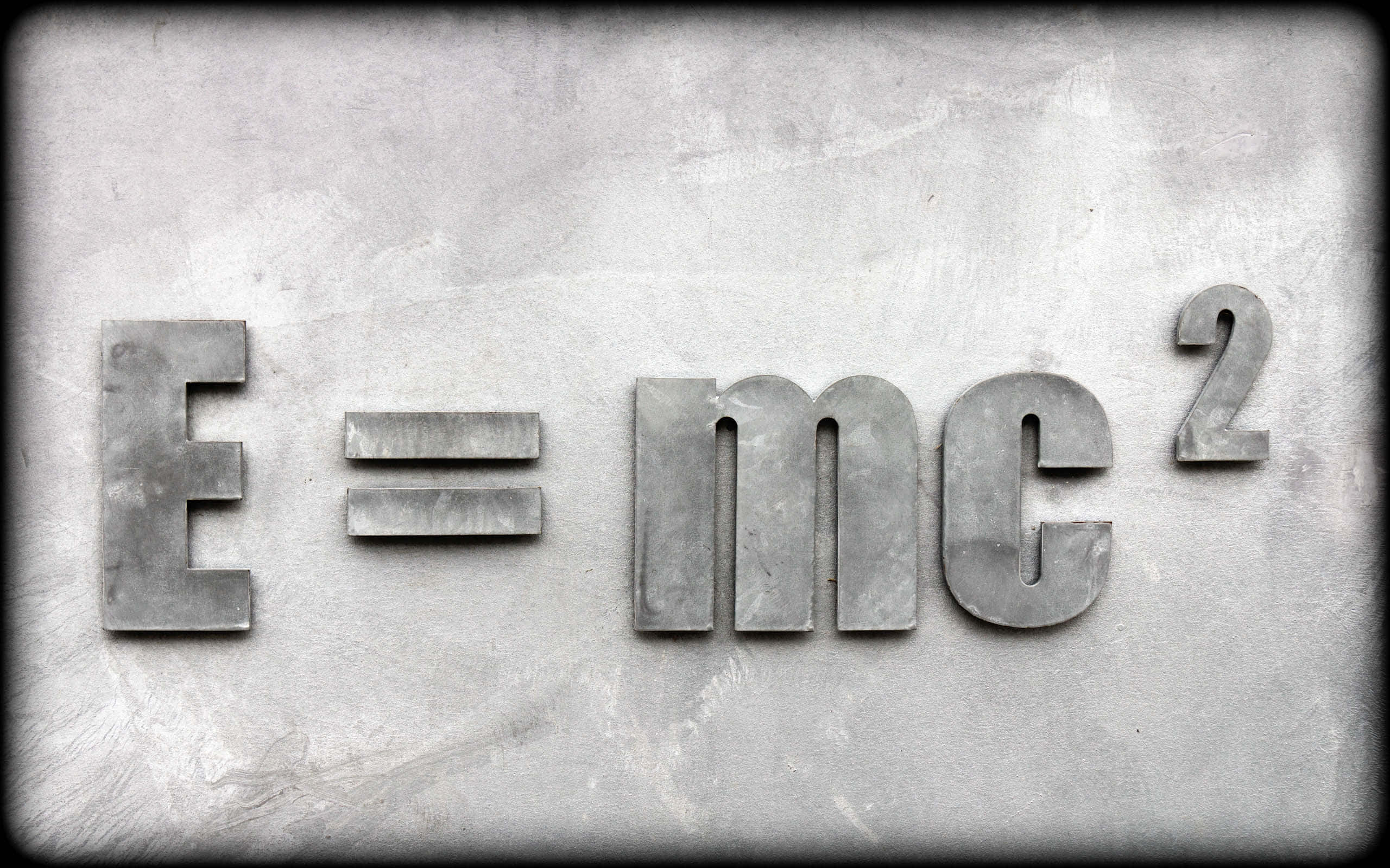 Physics 桌布 壁紙 — 金屬E=mc²字母安裝在風化的灰色混凝土牆上，帶有復古暈影效果。