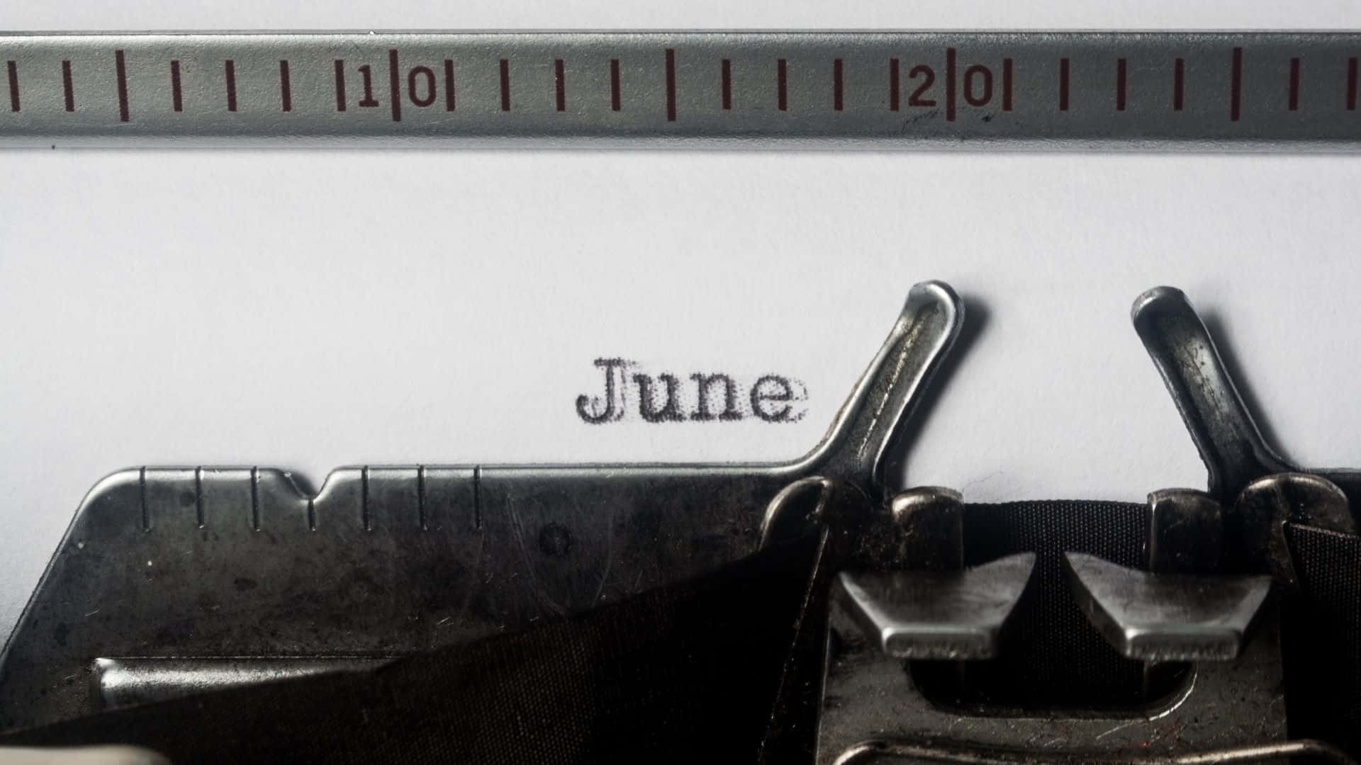 六月 桌布 壁紙 — 金屬尺下的白色紙上，一部復古打字機打出「June」一詞的特寫。
