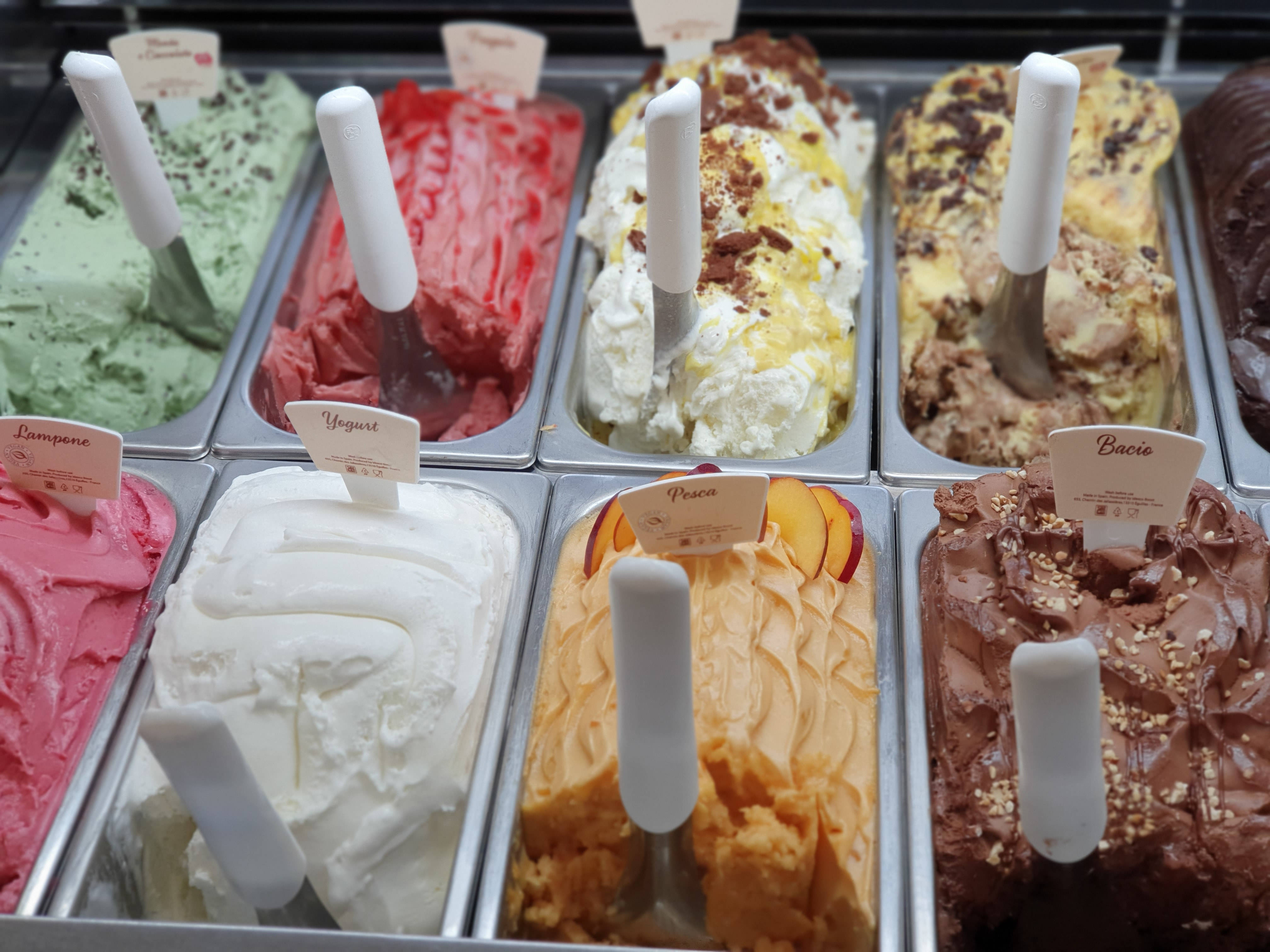 Ice Cream 桌布 壁紙 — 金屬桶中色彩繽紛的工匠義式冰淇淋，配有白色挖勺和口味標籤。