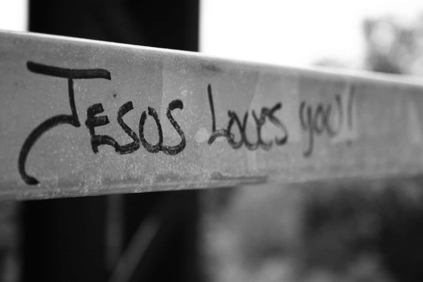桌布 壁紙 — 金屬欄杆上手寫文字「JESUS LOVES YOU!」的黑白特寫，背景模糊。
