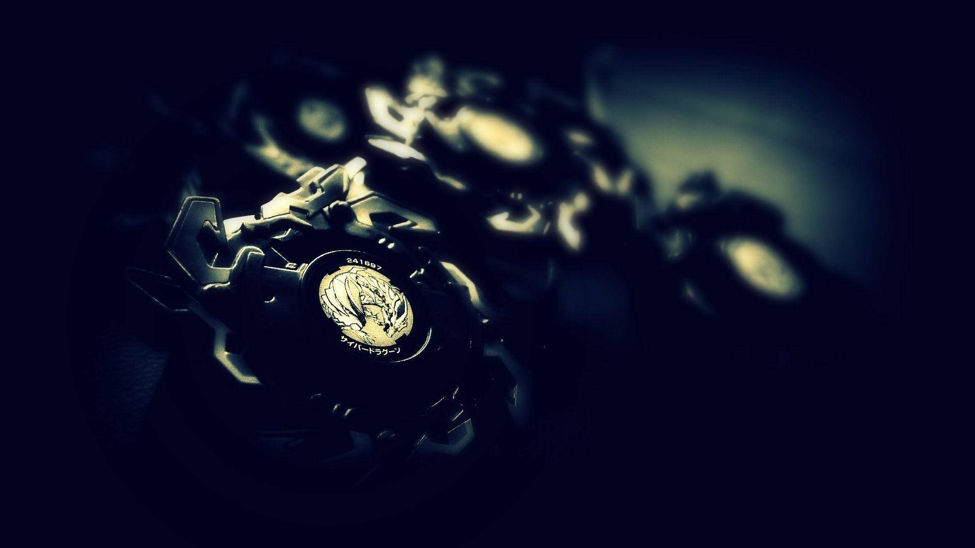 Beyblade 桌布 壁紙 — 金屬製Beyblade的特寫，帶有發光金色點綴，背景是暗色模糊。
