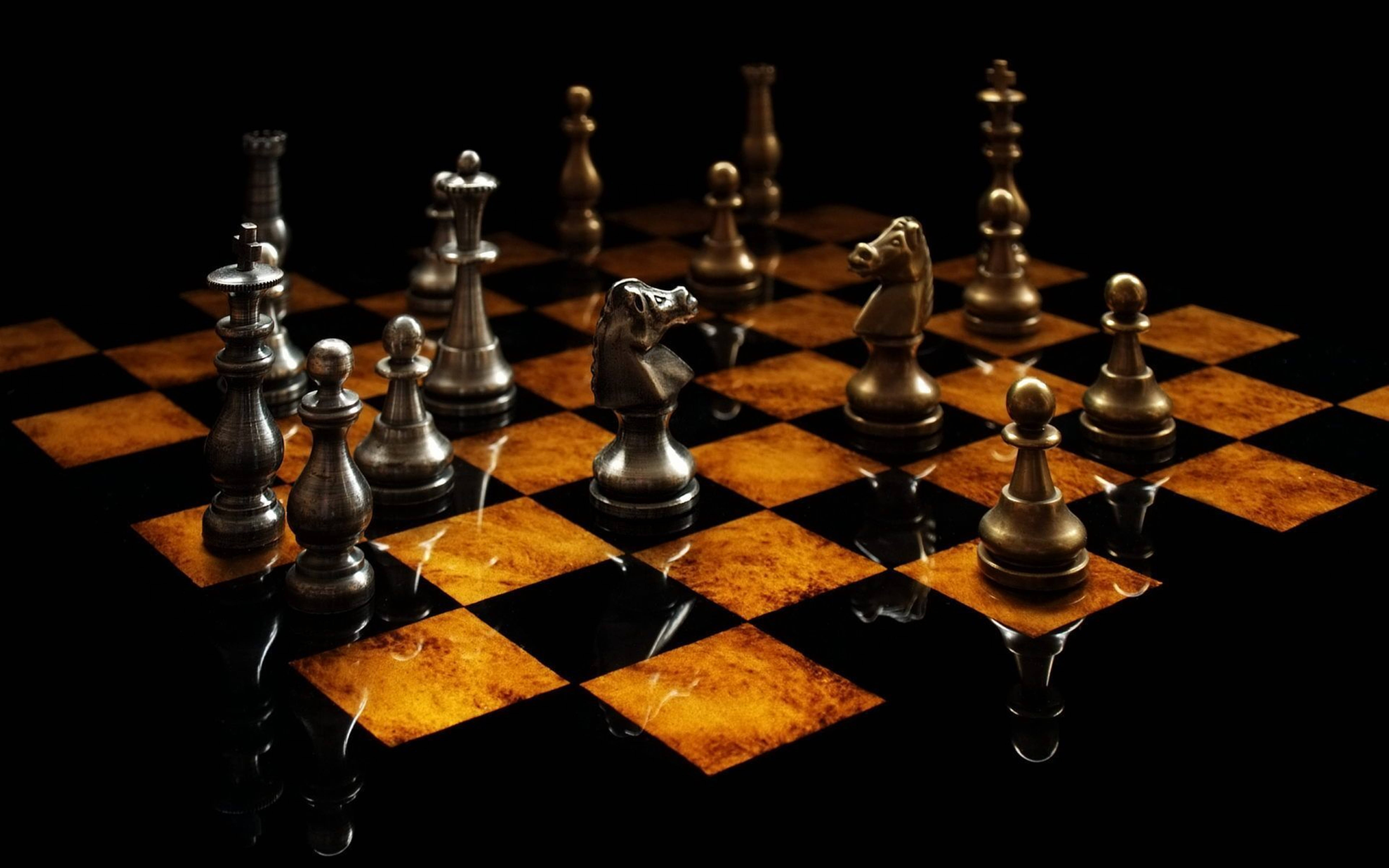 3D 桌布 壁紙 — 金屬西洋棋棋子立於光面棋盤上，背景為純黑色，燈光效果戲劇性。