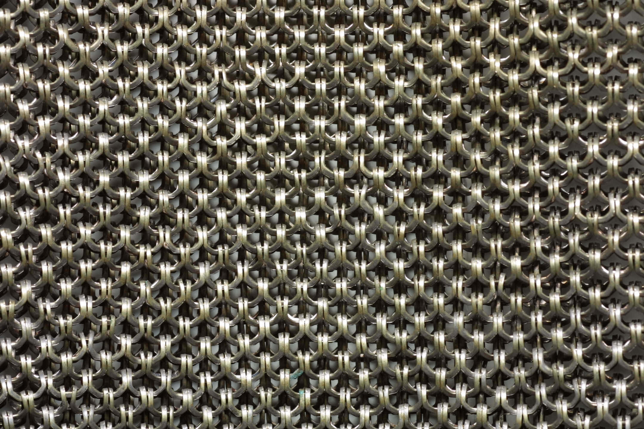 Aluminium 桌布 壁紙 — 金屬鎖子甲鏈環緊密相扣形成重複幾何圖案的特寫，帶有反射高光。