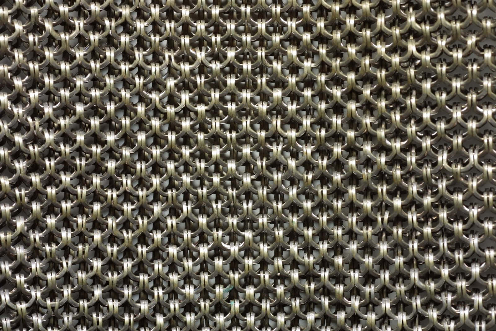 metal 桌布 壁紙 — 金屬鎖子甲鏈環緊密相扣的特寫，形成重複幾何圖案，帶有反射高光。