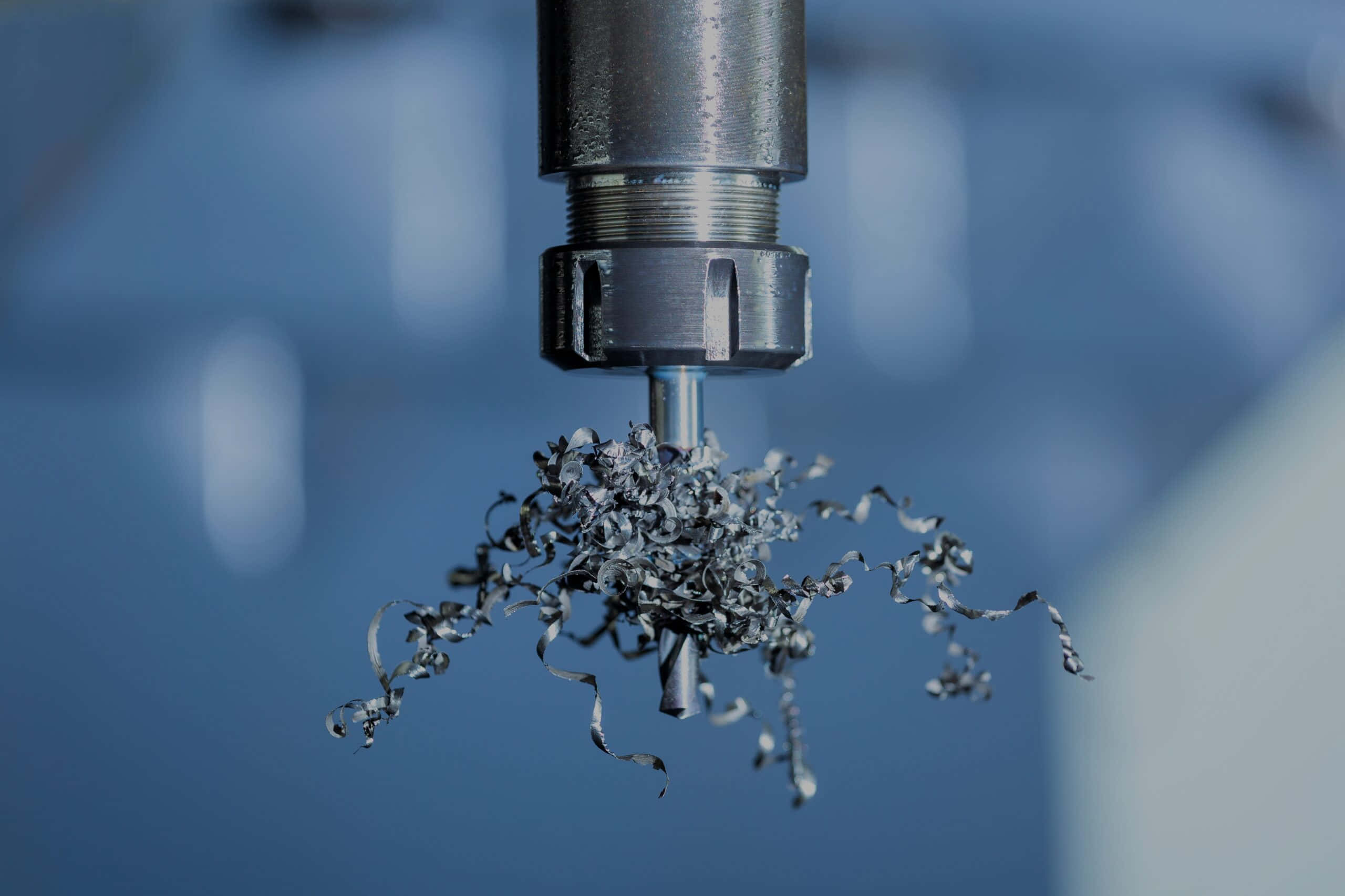 Machine 桌布 壁紙 — 金屬鑽頭旋轉並在模糊的藍色工業背景下噴出螺旋狀金屬碎屑的特寫。