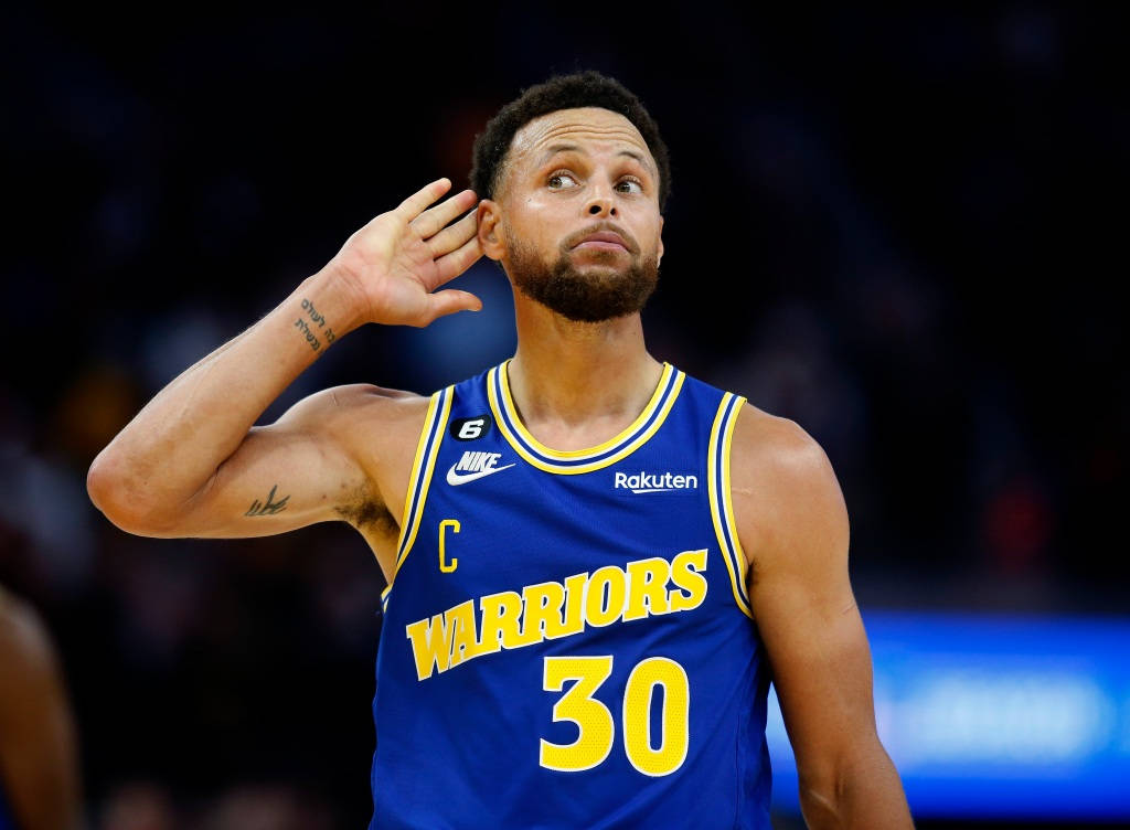 NBA 桌布 壁紙 — 金州勇士隊球員史蒂芬柯瑞身穿藍色30號球衣，在場館燈光下的一場籃球比賽中舉手敬禮。