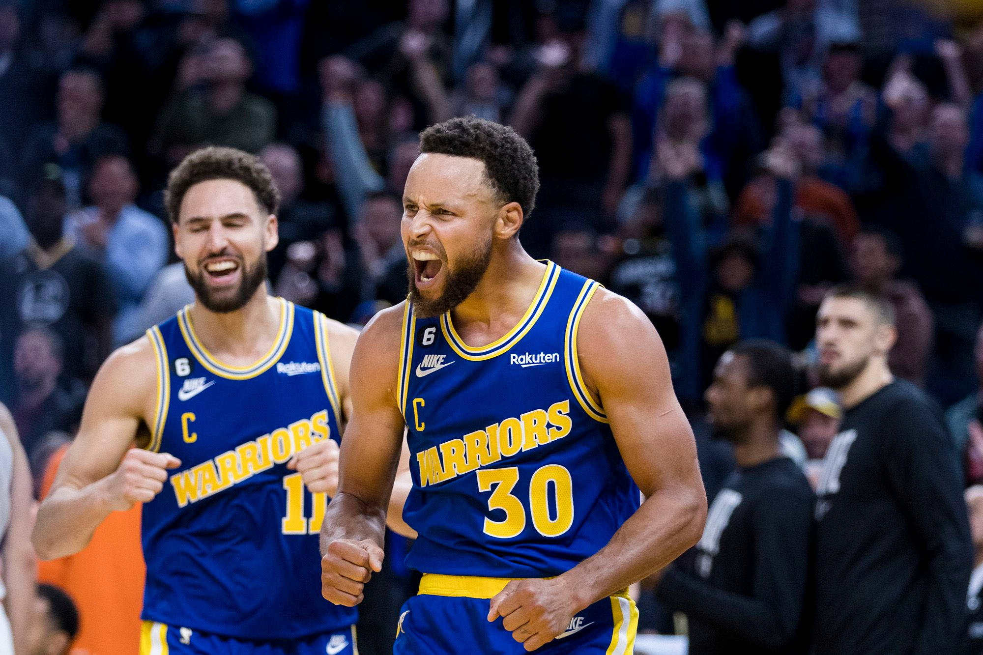 NBA 桌布 壁紙 — 金州勇士隊球員在明亮的場館燈光下，於擠滿人的籃球場上熱烈慶祝。