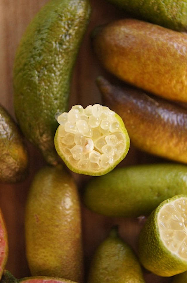 Fruits 桌布 壁紙 — 金桔的特寫，其中一個切開一半，露出半透明的分瓣果肉，放在木質表面上。