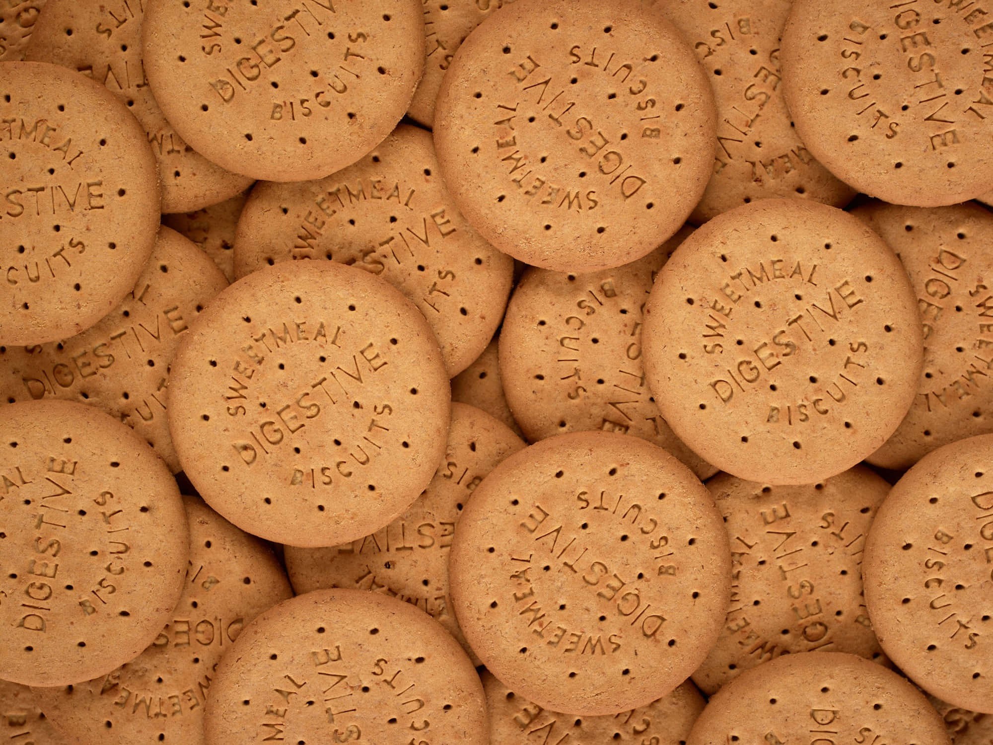 餅乾 桌布 壁紙 — 金棕色消化餅乾的特寫，上面印有 'SWEETMEAL DIGESTIVE BISCUITS' 字樣和點狀孔洞。