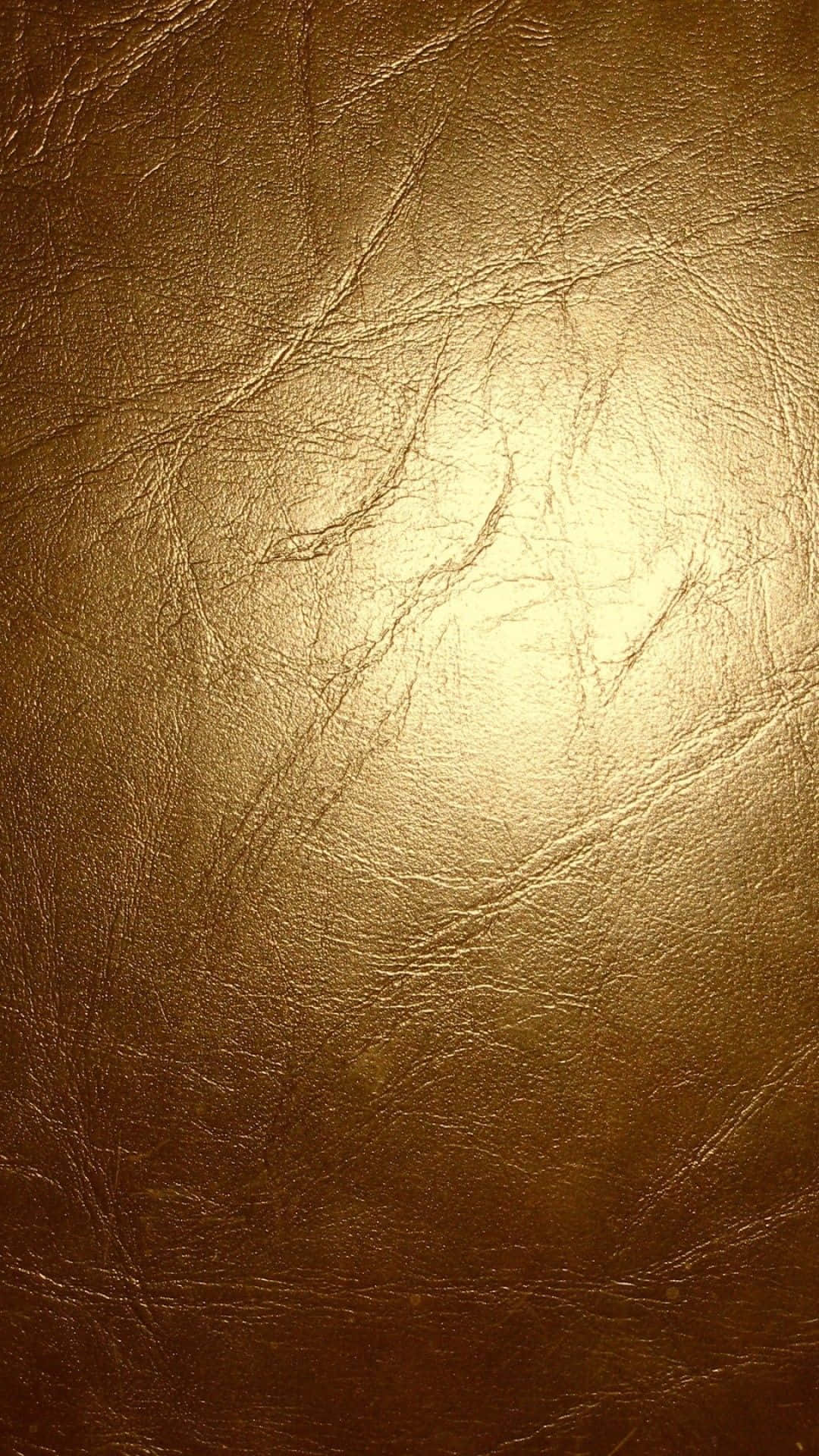 Metallic Gold 桌布 壁紙 — 金棕色皮革的特寫，在柔和光線下呈現自然皺褶和溫暖高光。