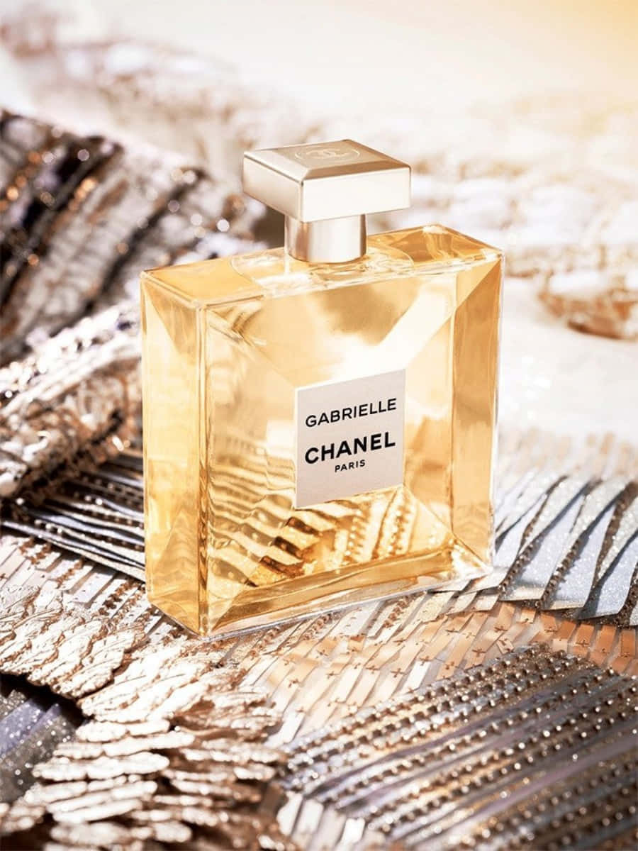 Chanel 桌布 壁紙 — 金色 Chanel Gabrielle 香水瓶在溫暖燈光下閃耀於閃爍的金屬布料表面。