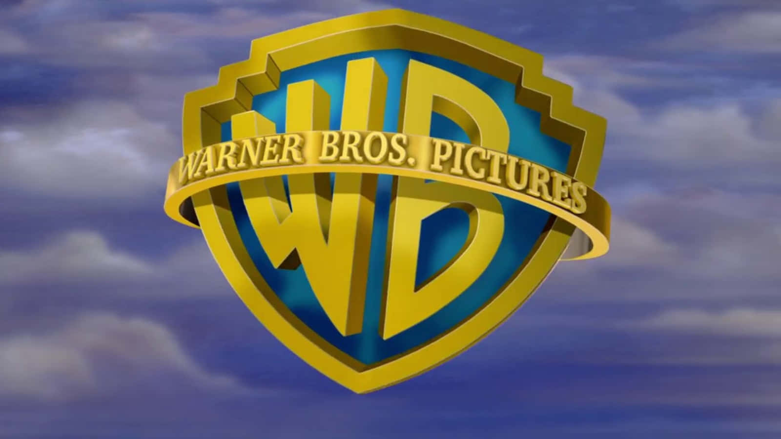 Warner Bros 桌布 壁紙 — 金色 Warner Bros Pictures 盾牌標誌在戲劇性燈光下漂浮在陰天藍色天空中。
