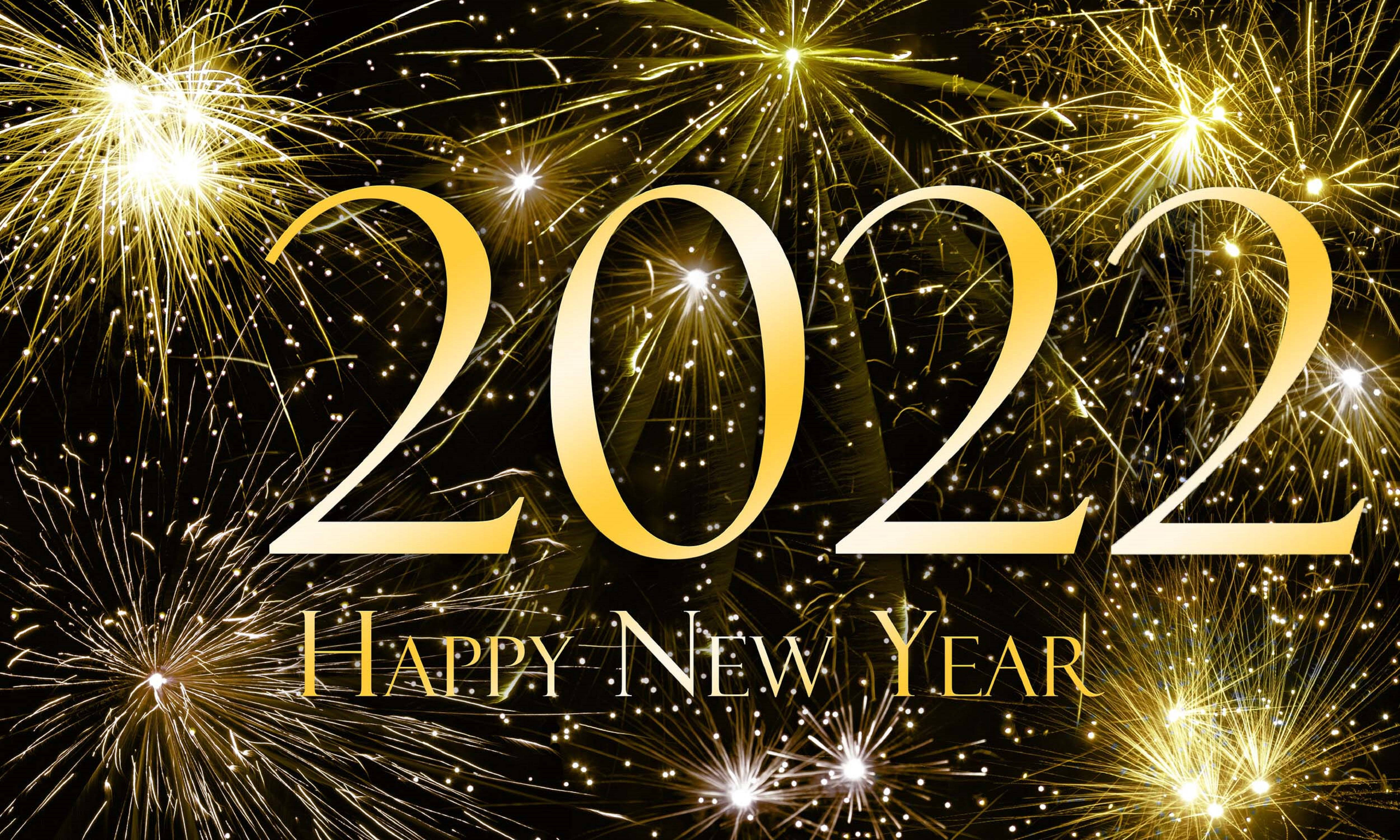 New 桌布 壁紙 — 金色2022文字在黑色背景上發光，背景充滿閃爍的煙火慶祝新年。
