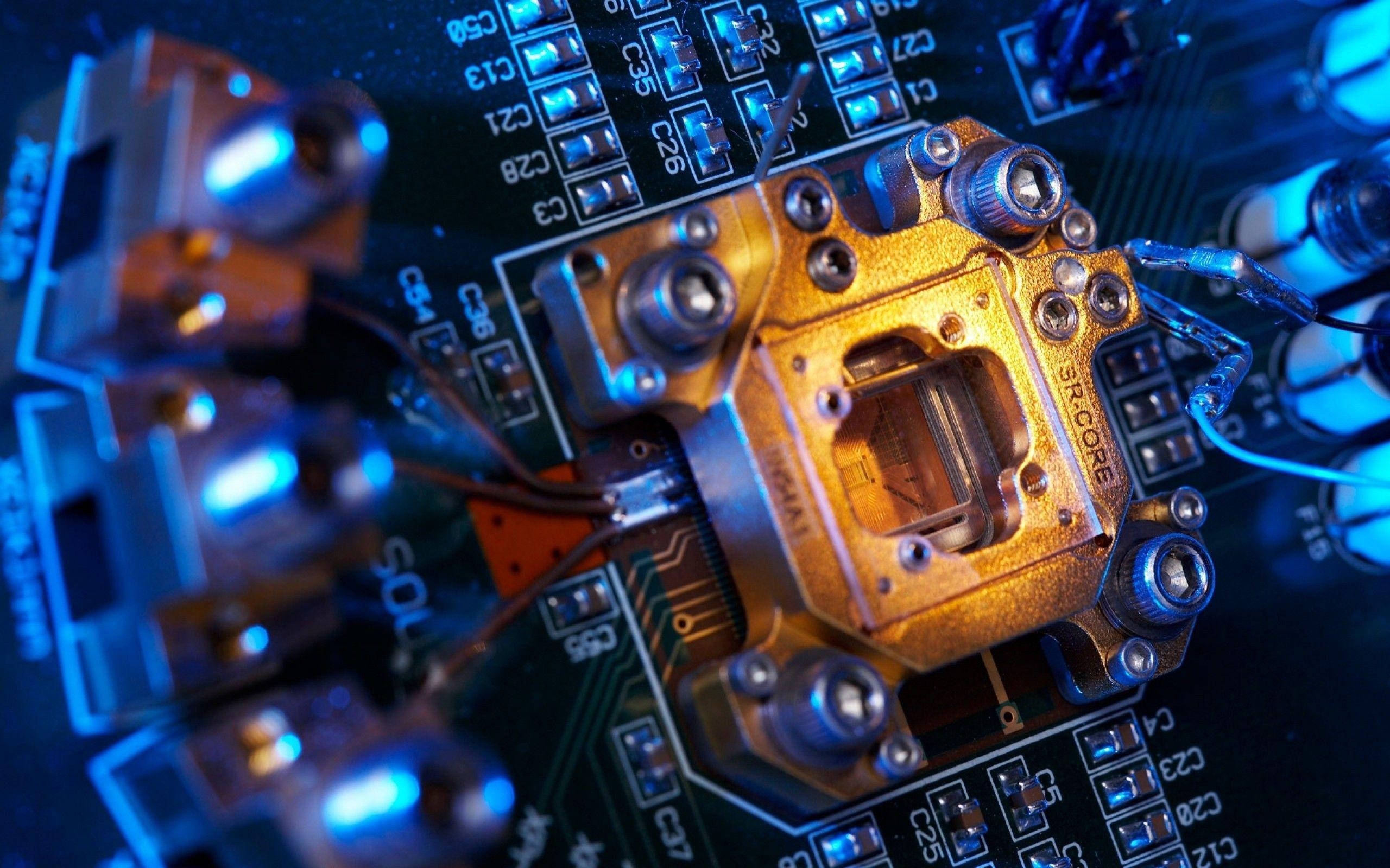 Motherboard 桌布 壁紙 — 金色CPU散熱器在電路板上發出電藍色LED燈光的特寫。