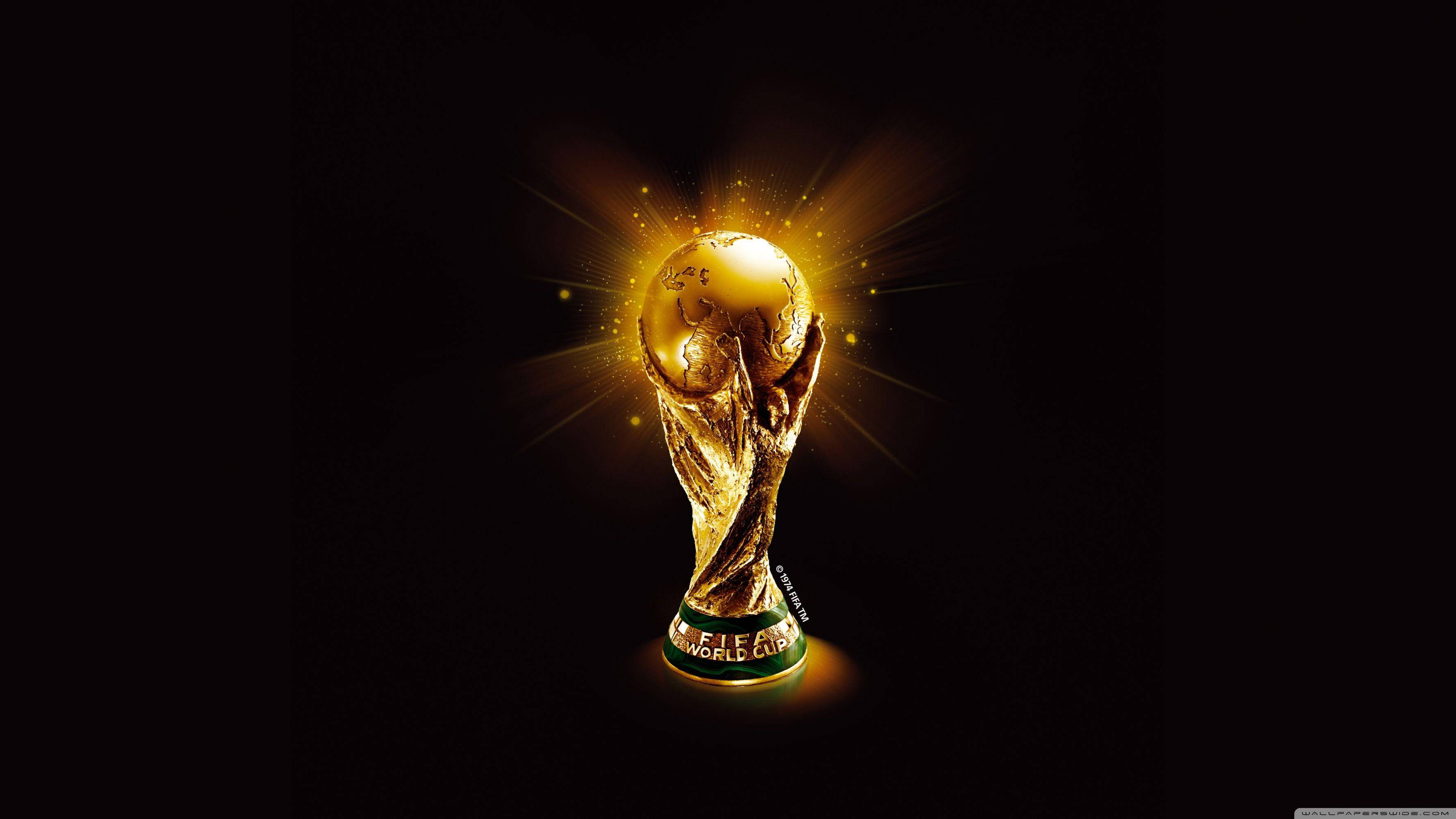 World 桌布 壁紙 — 金色FIFA世界盃獎盃在黑色背景上散發出明亮的光芒，並帶有發光粒子。