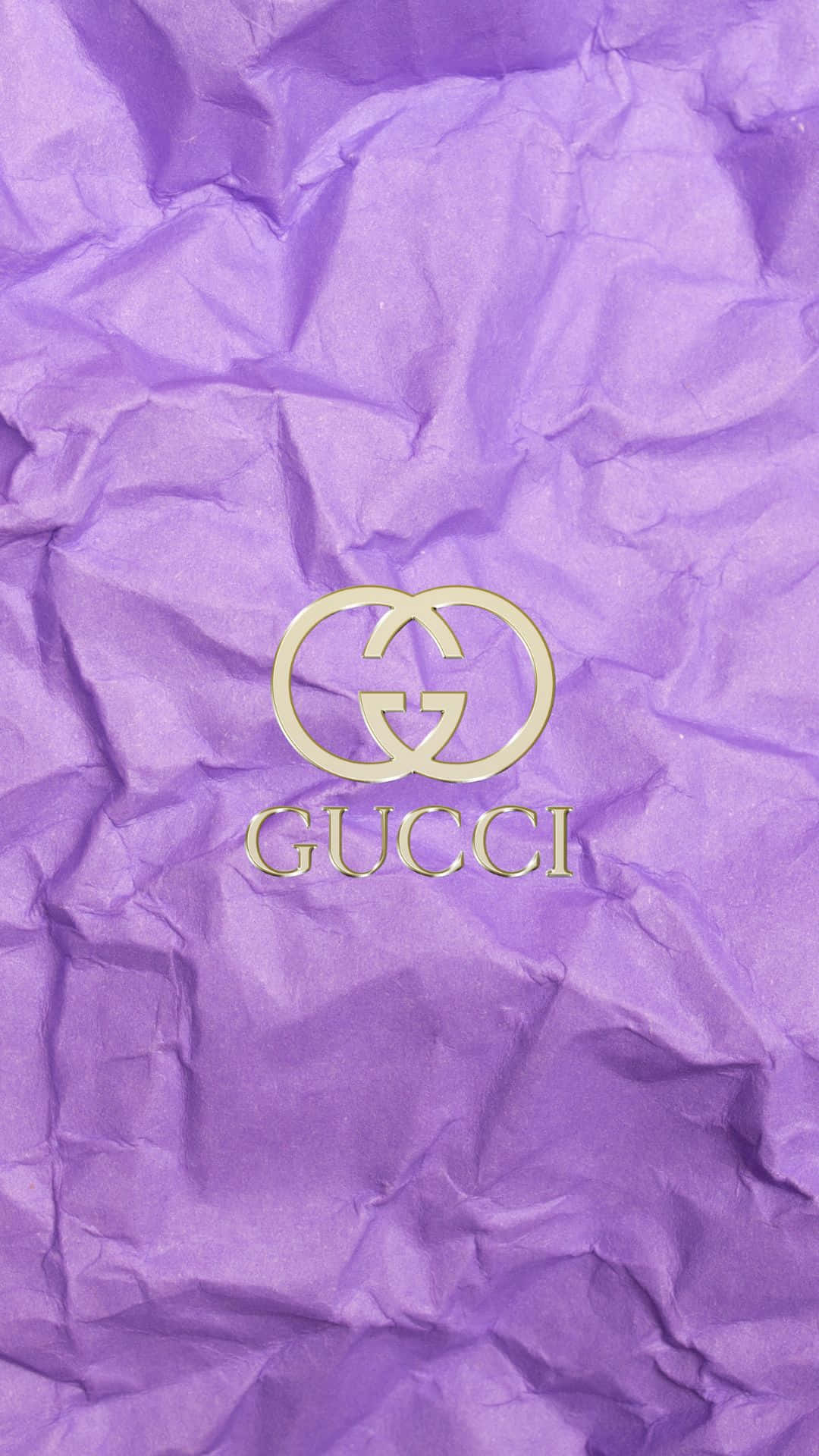 標誌 桌布 壁紙 — 金色Gucci標誌放置在帶有紋理的皺褶紫色紙上，光線柔和。