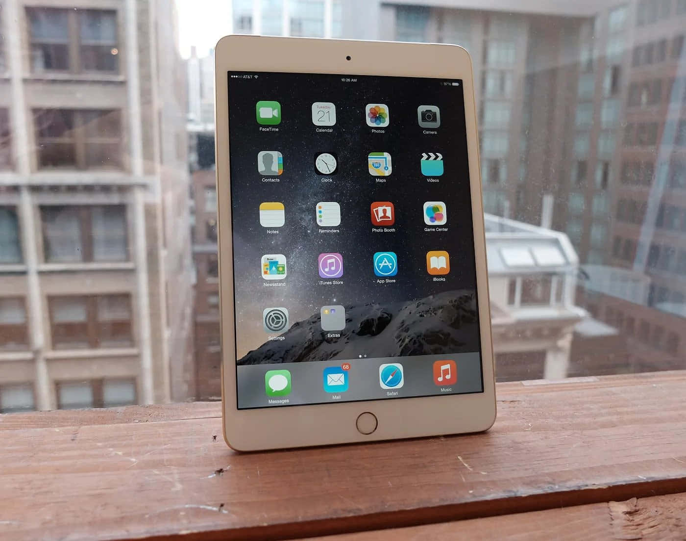 iPad 桌布 壁紙 — 金色iPad放在木窗台上，顯示應用程式圖示，背後是模糊的城市建築。