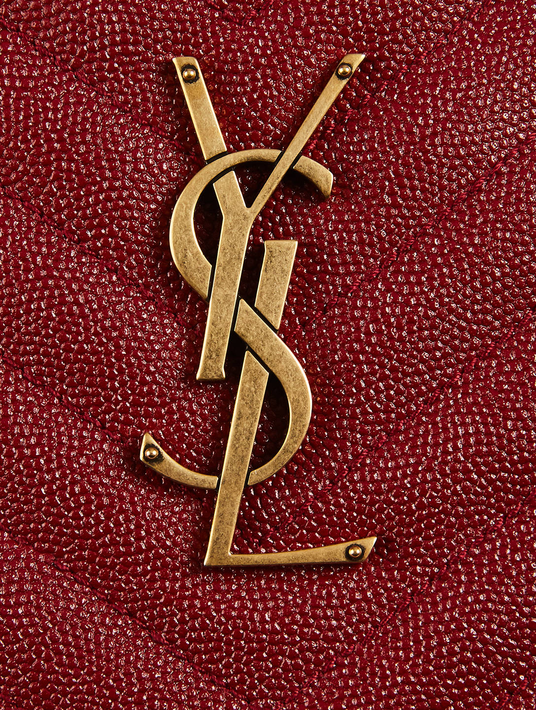 Ysl 桌布 壁紙 — 金色YSL字母組合標誌的特寫，位於紋理深紅色皮革上。