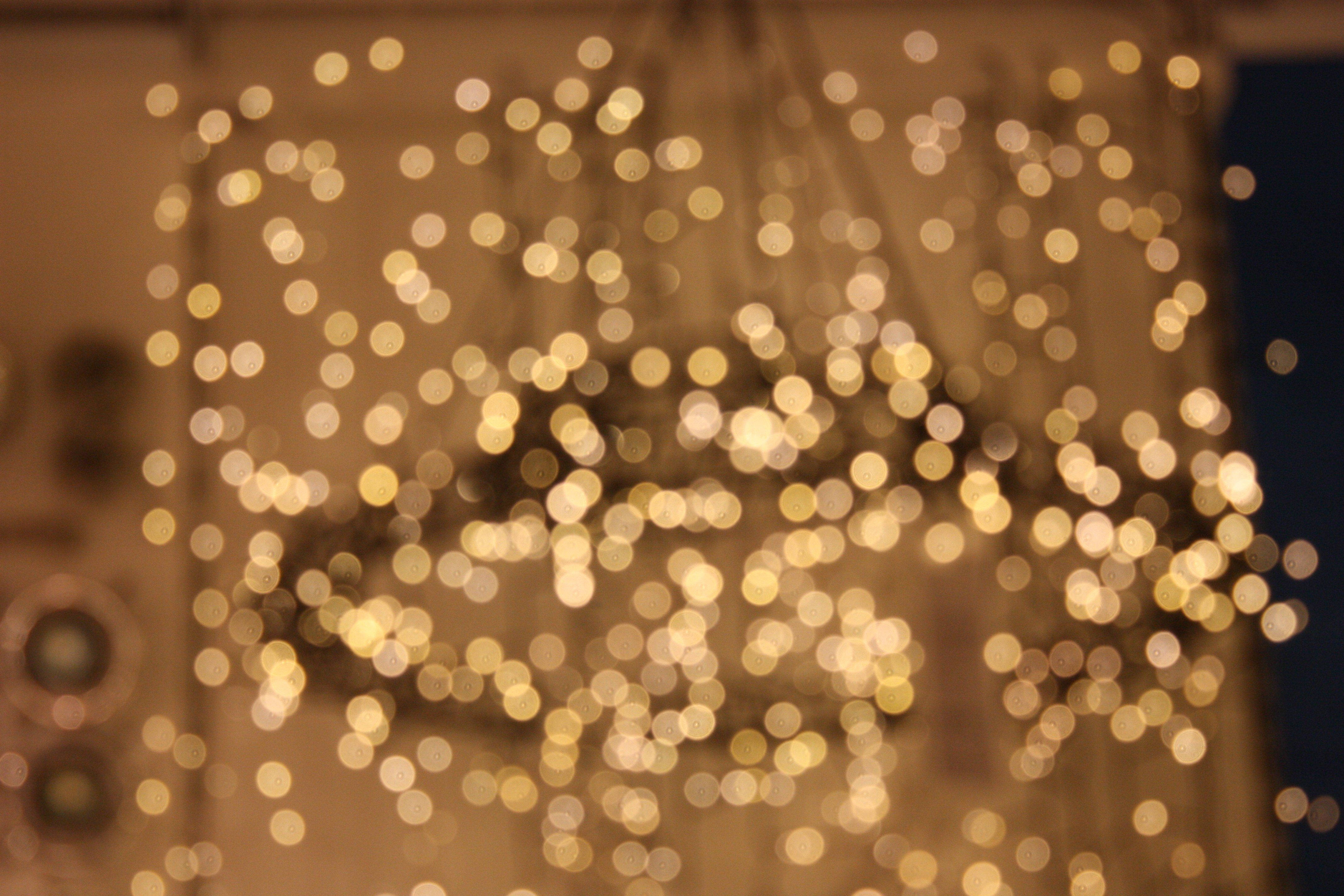 Christmas Lights Aesthetic 桌布 壁紙 — 金色串燈在模糊的室內背景下柔和發光的夢幻散景效果。