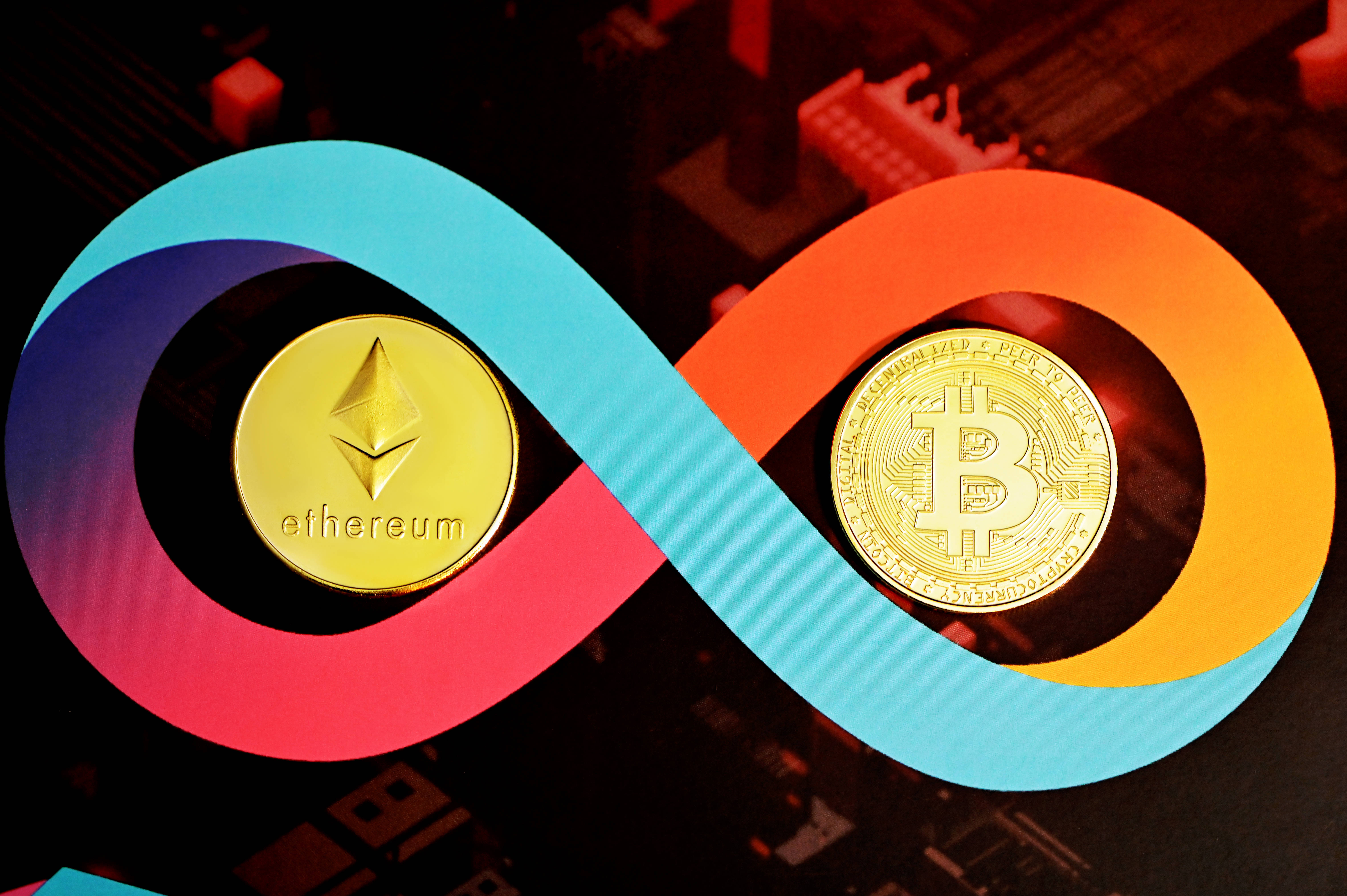Cryptocurrency 桌布 壁紙 — 金色以太坊和比特幣硬幣位於電路板背景上的彩色無限符號內。