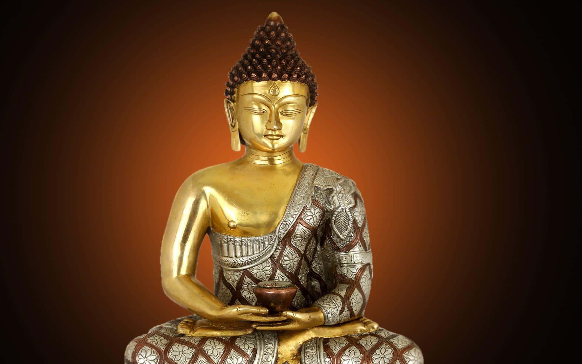 Gautama Buddha 桌布 壁紙 — 金色佛像以冥想姿勢呈現，身穿精緻銀色長袍，背景為溫暖漸變色。