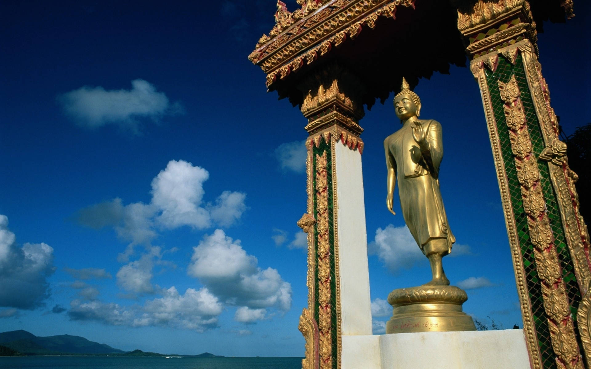Statue Aesthetic 桌布 壁紙 — 金色佛像在藍天白雲和遠方海平線下寧靜地站立。